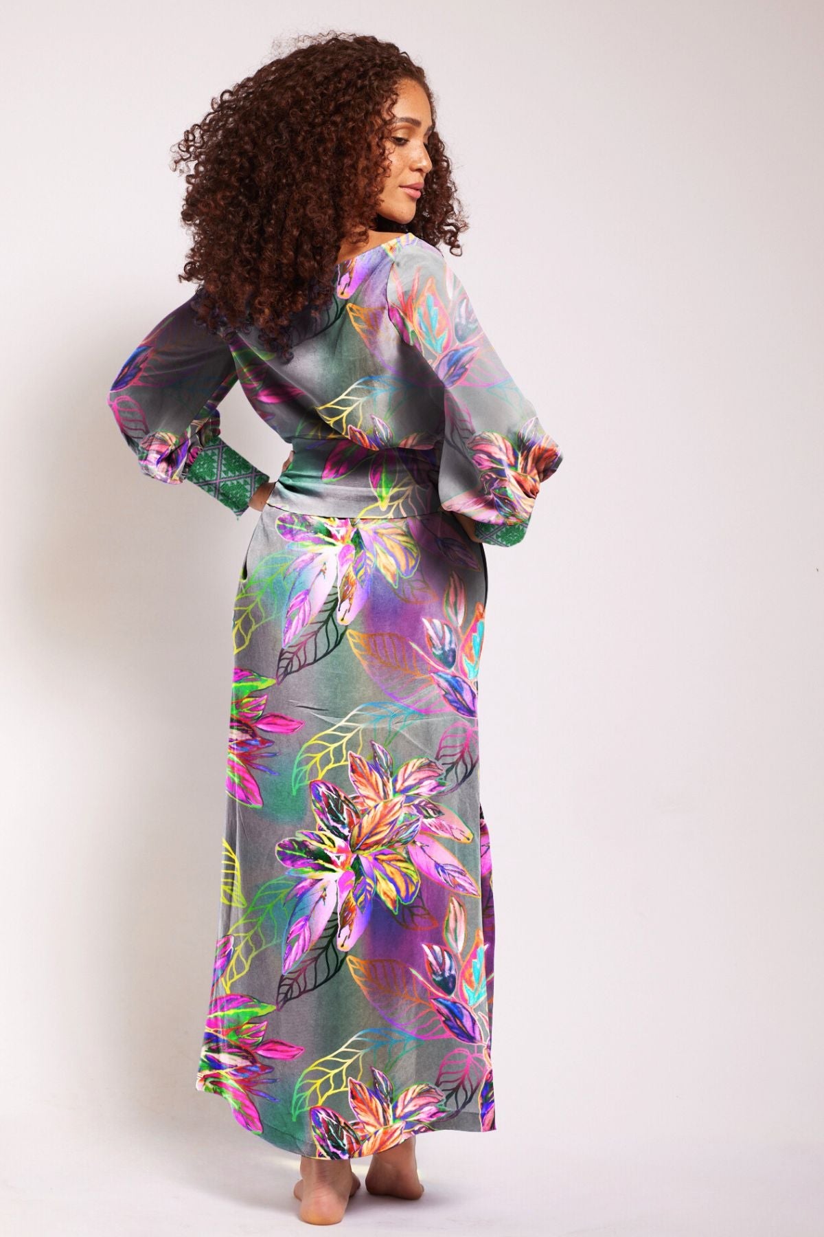 back profile of woman wearing all over tropical printed kaftan duster with embroidered cuffs made from recycled materials