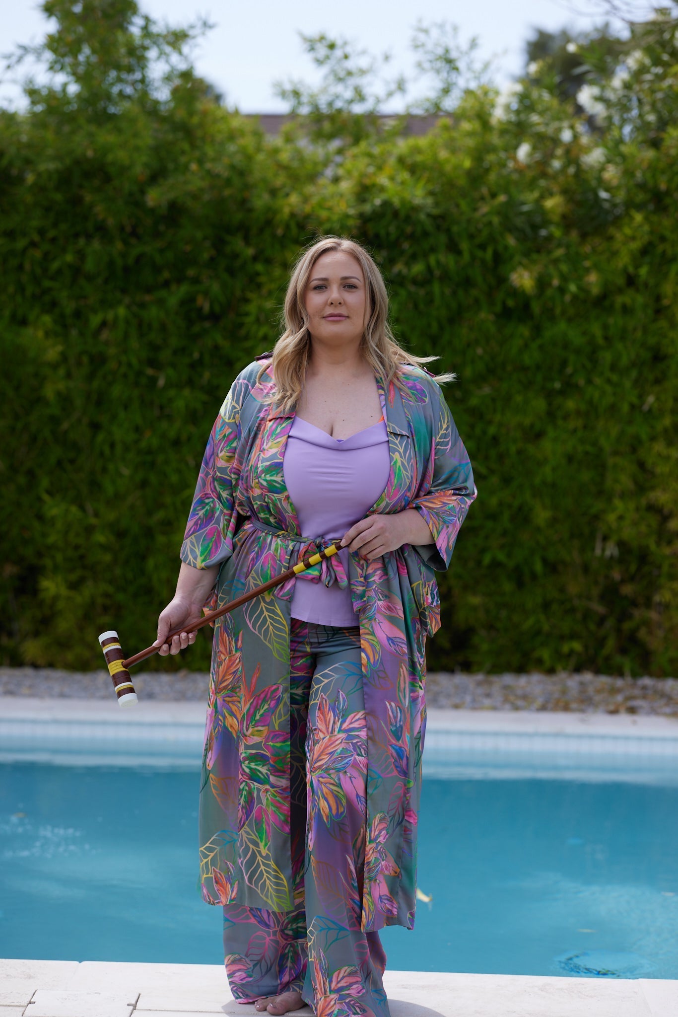 Woman standing poolside wearing an all over tropical print kimono duster made from recycled materials