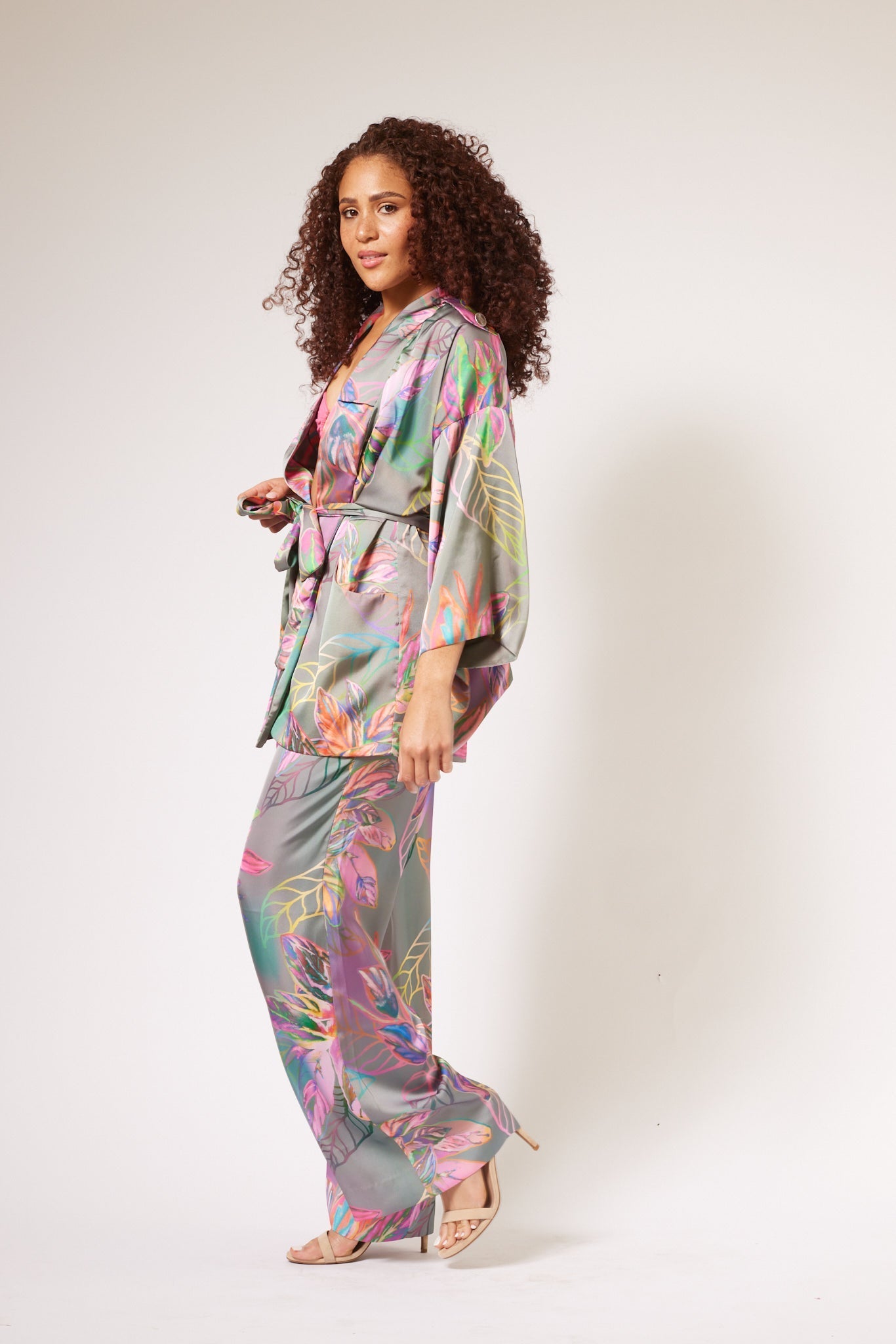 Side profile of woman wearing an all over tropical print kimono duster and yacht pants made from recycled materials