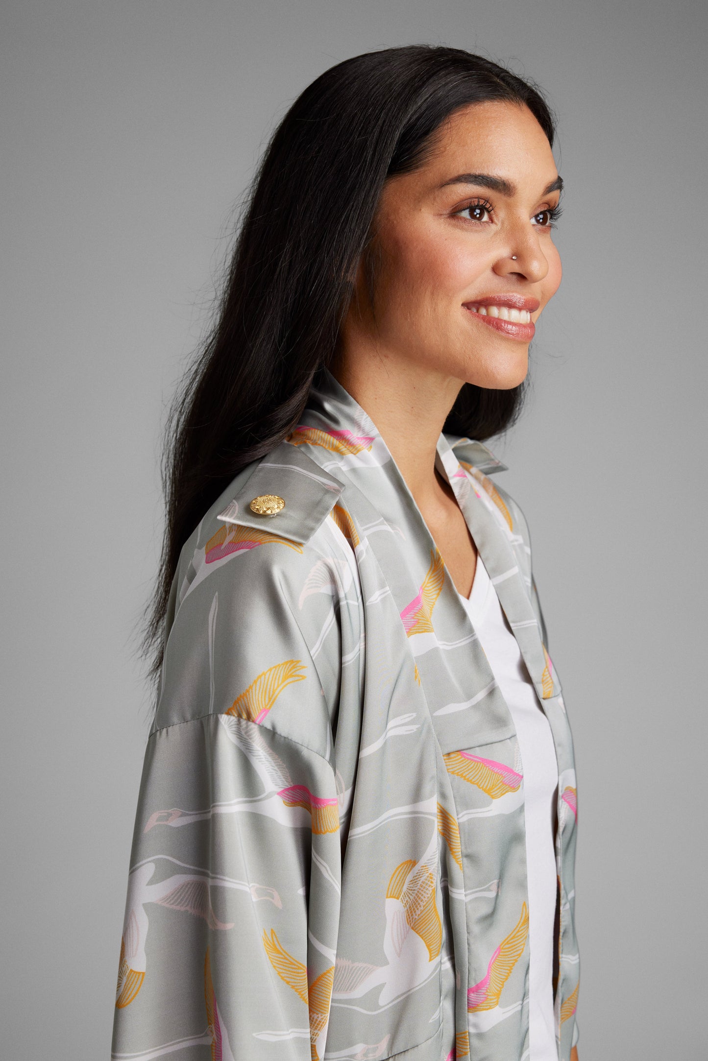 woman standing with hands on her face wearing a grey and pink colored crane patterned kimono duster made from recycled materials 4