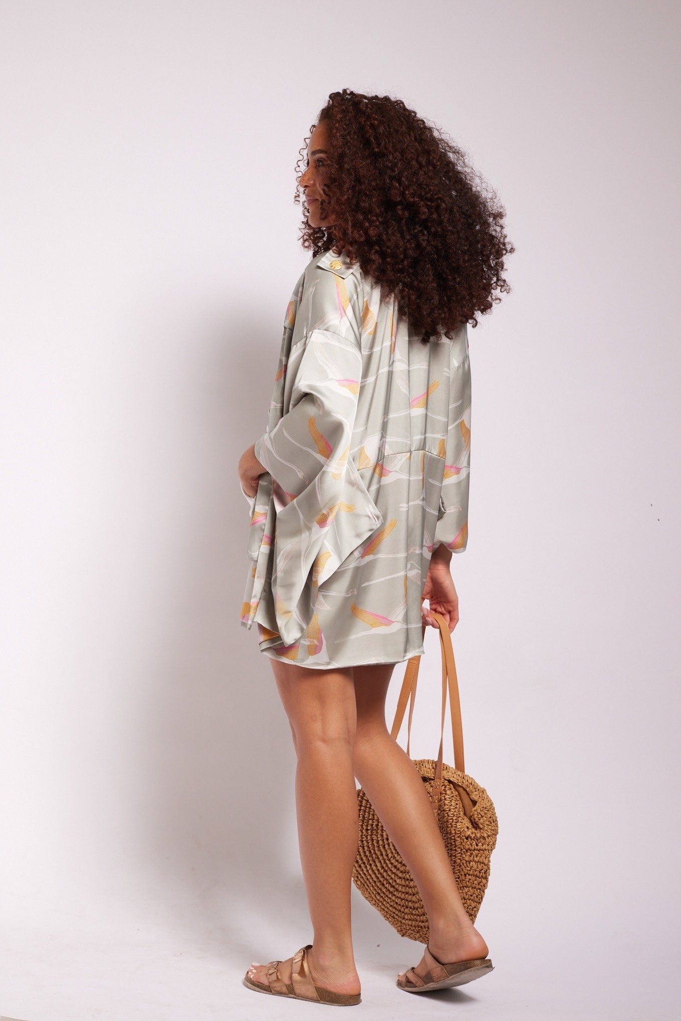 Woman holding a purse wearing a grey pink and gold colored crane print kimono duster and matching tulip shorts