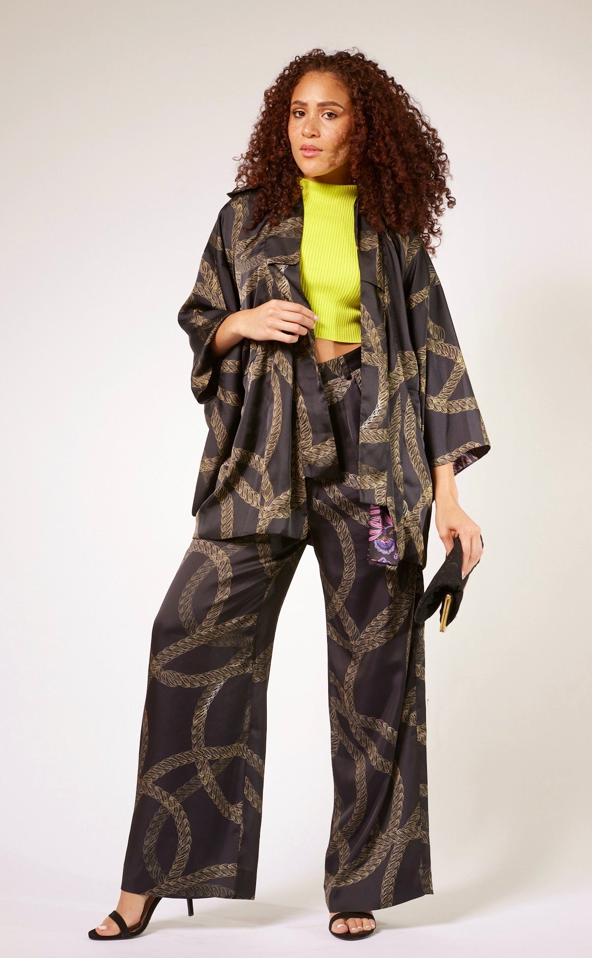 woman modelling black and gold chains printed kimono duster with matching yacht slacks made from recycled materials 2