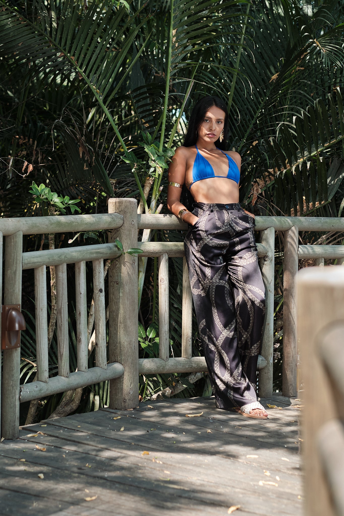 woman on a bridge wearing black and gold chain printed yacht slacks made from recycled textiles