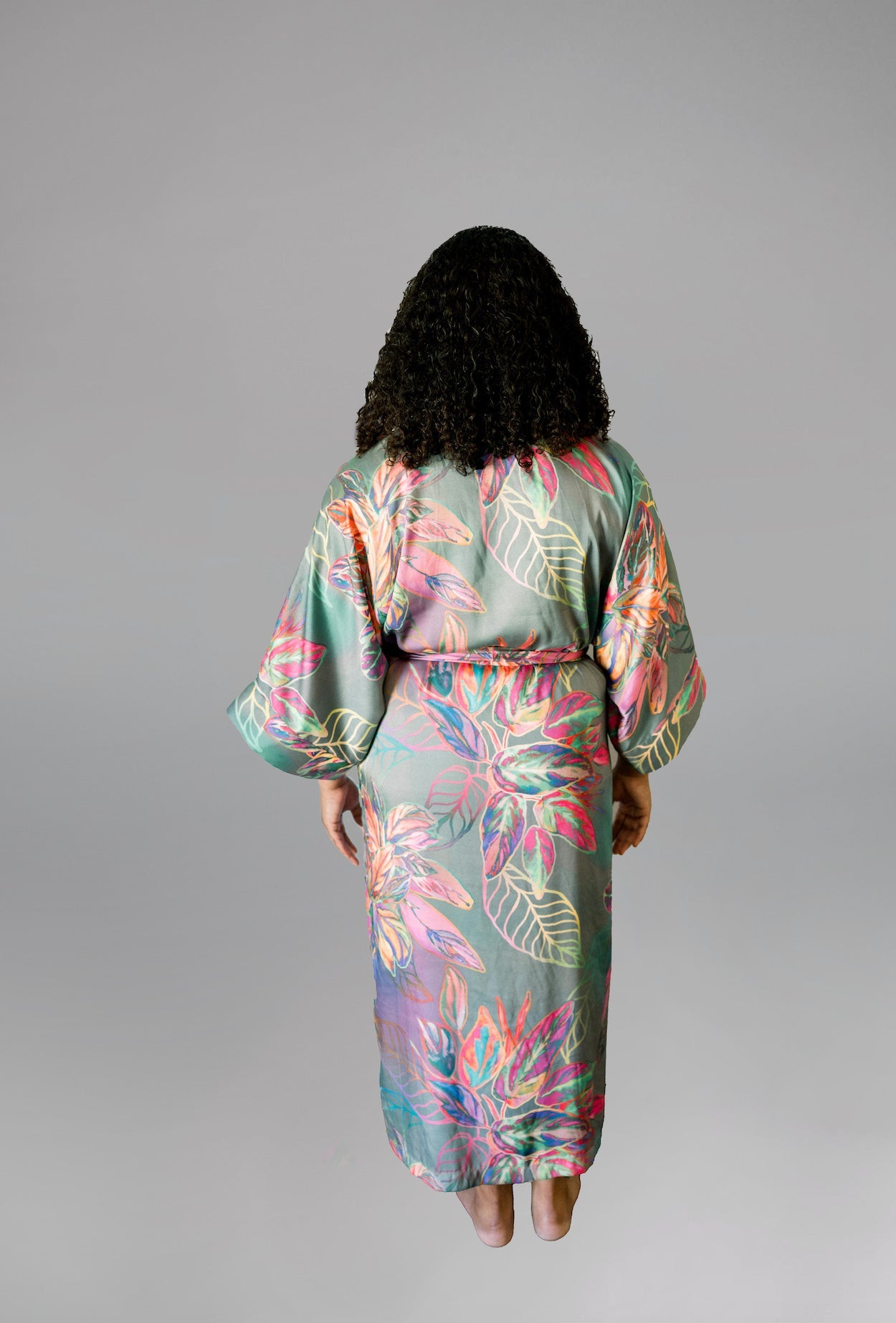 Woman wearing kimono robe in Carmen back profile view hands in her pockets