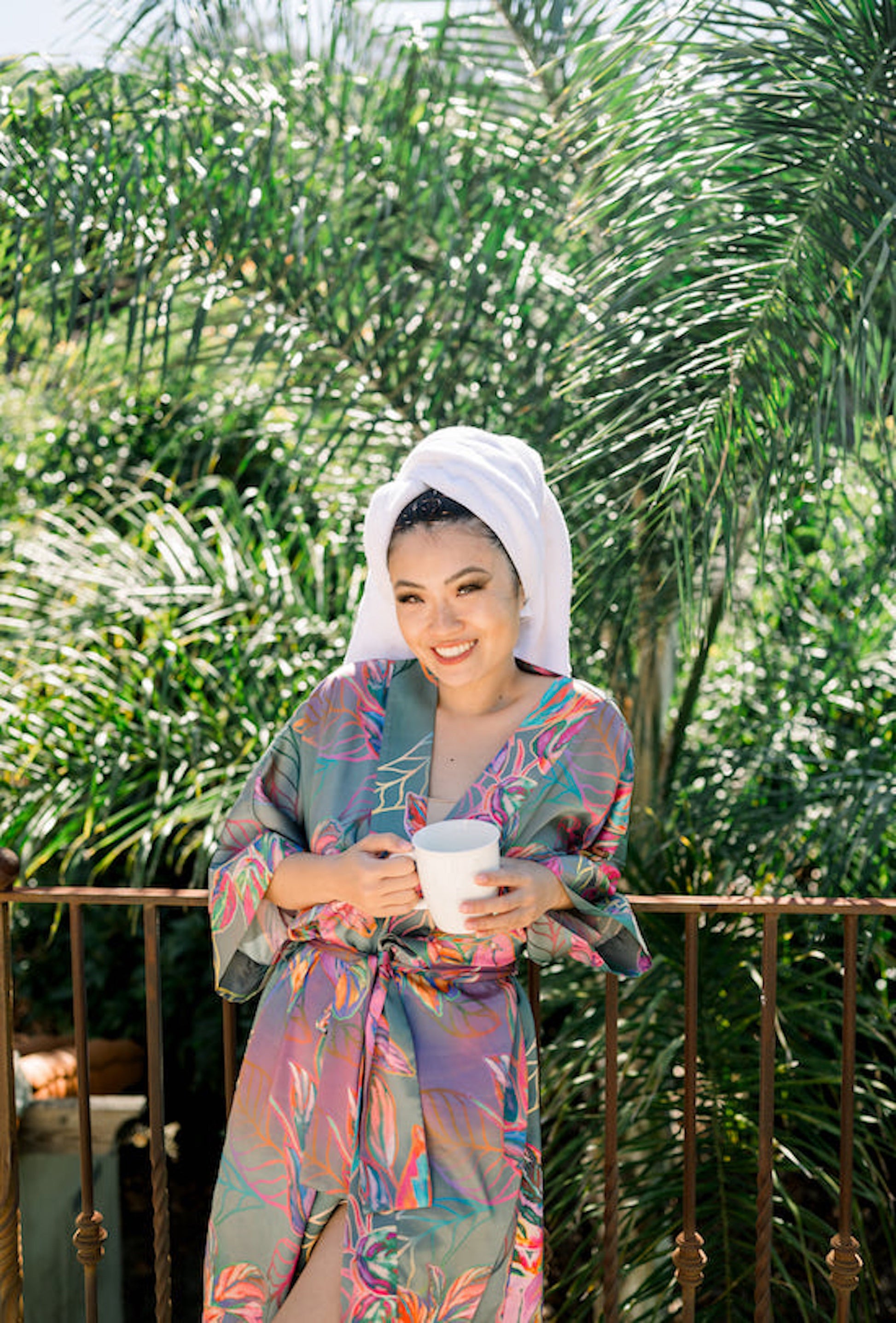Woman wearing kimono robe in Carmen outside leaning on gate wearing towel on her head