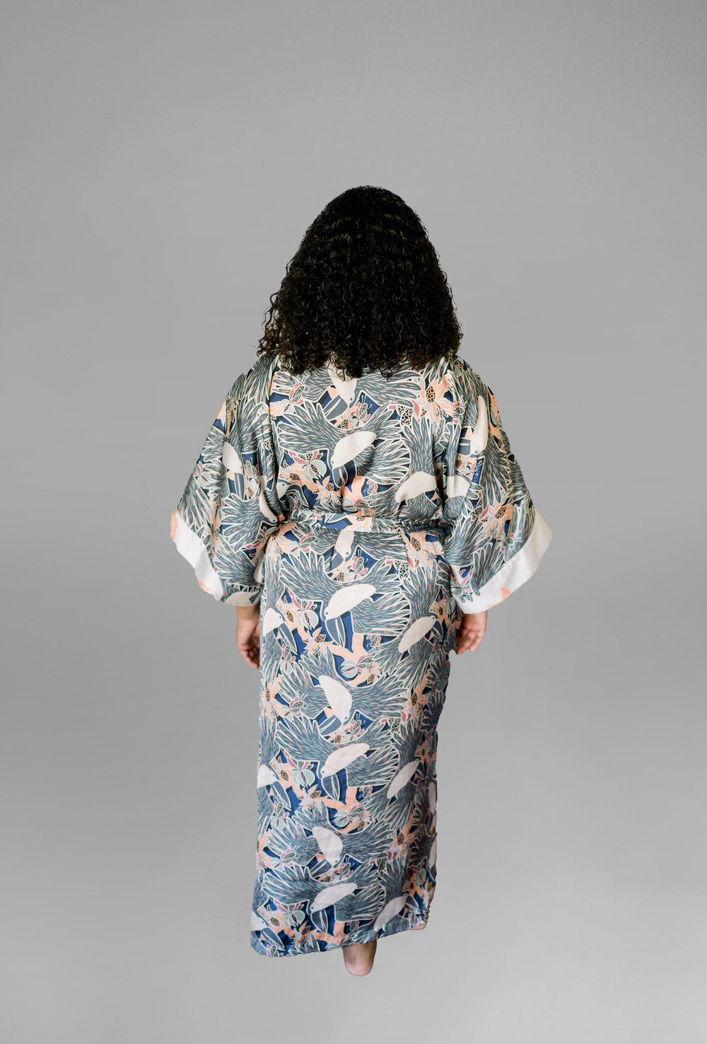 Woman wearing kimono robe in navy toucans back profile view with hands at her side