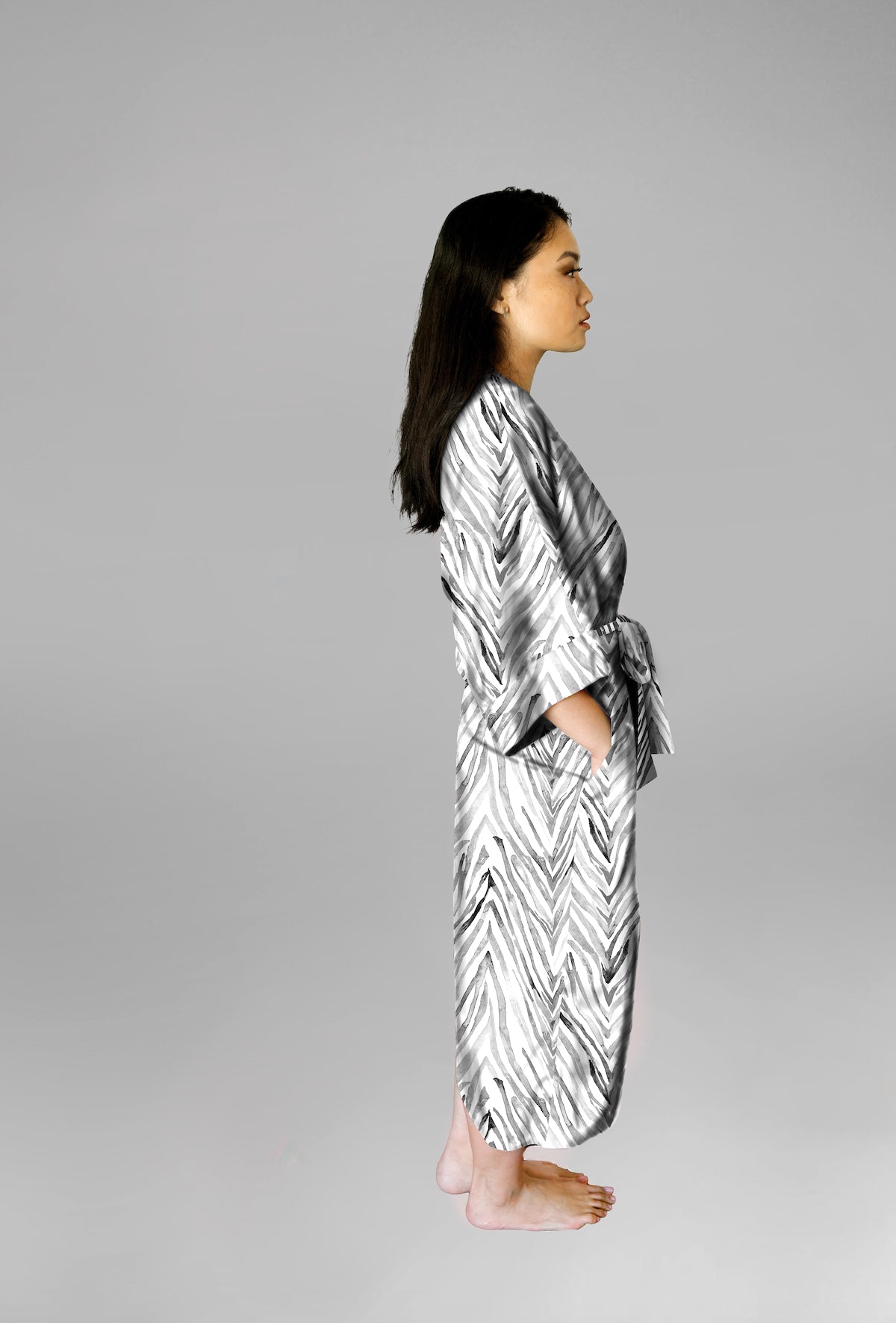 Woman wearing kimono robe in Zebra side profile view with her hands in her pockets