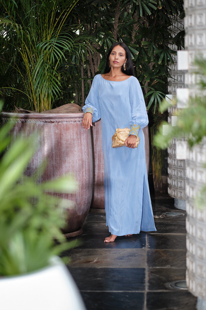 woman outside patio wearing lavender kaftan duster with embroidered sleeves made from recycled materials