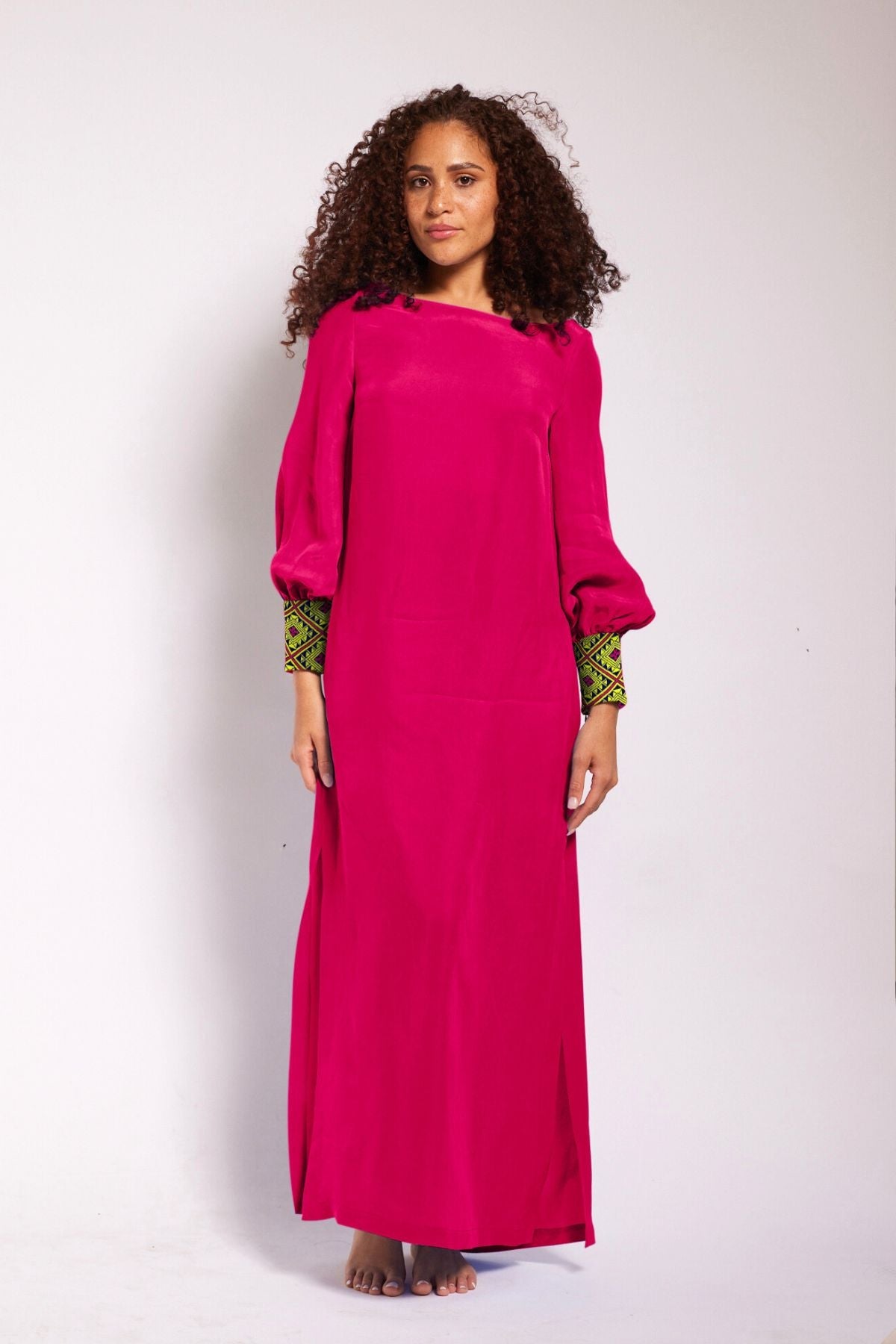 front profile view of woman wearing a magenta kaftan duster with embroidered sleeves made from recycled materials 2