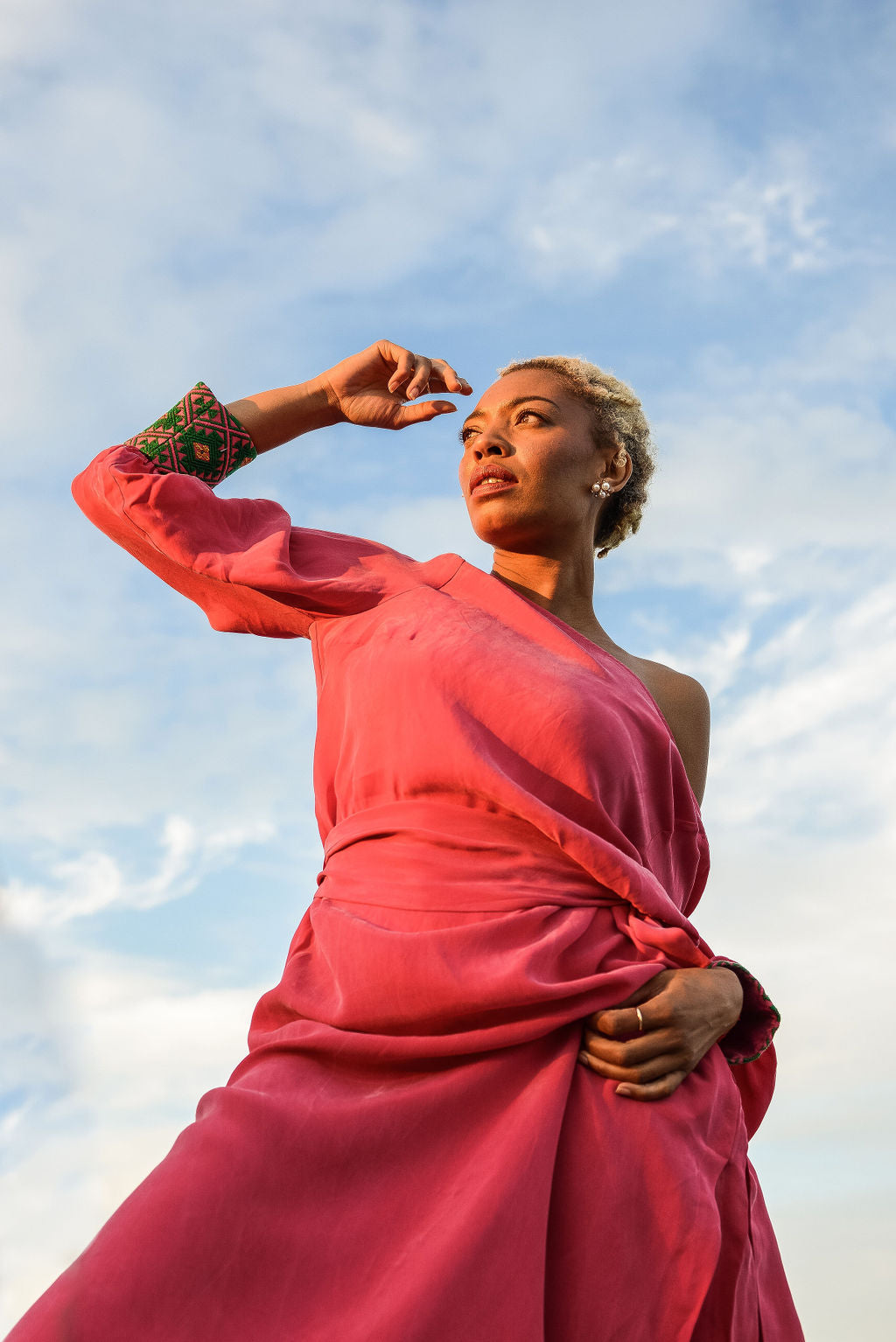 woman modelling outside wearing a magenta kaftan duster with embroidered sleeves made from recycled materials 6