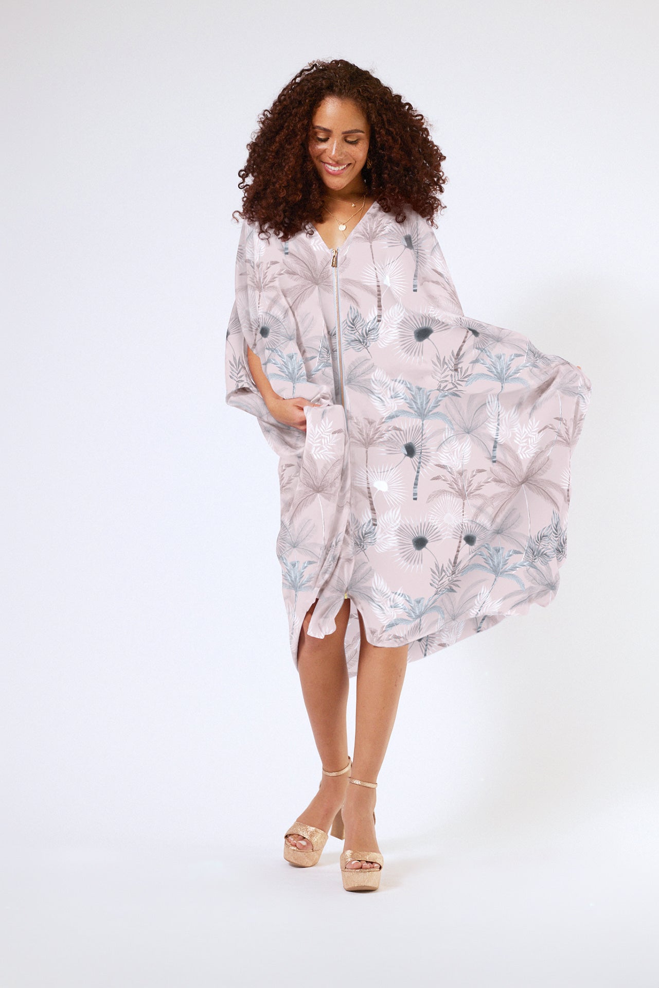 front view of woman wearing all over blush tropical print kaftan duster with front zipper made from recycled materials 2