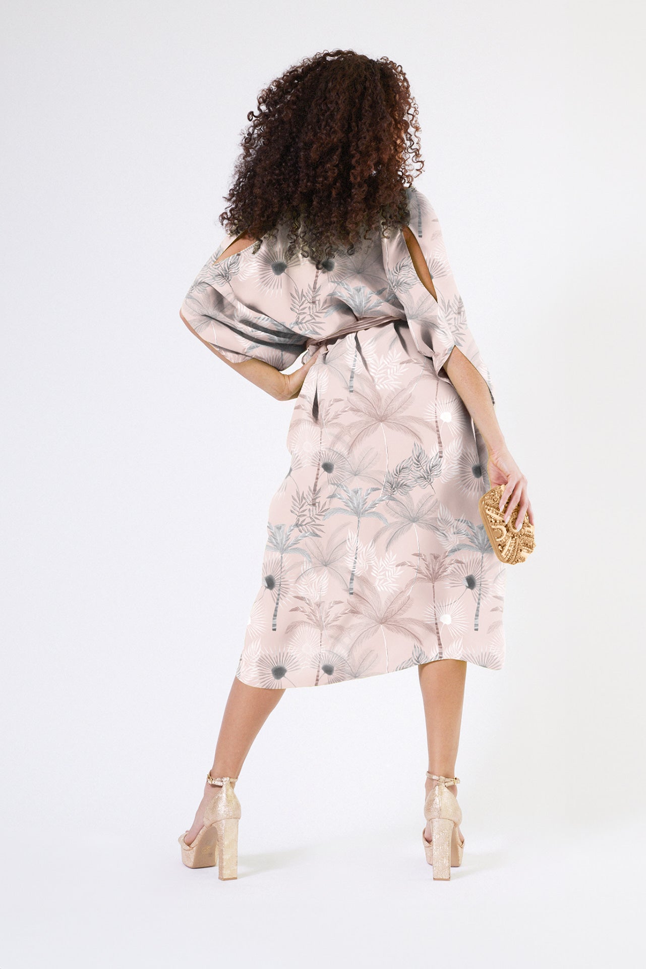 back view of woman wearing all over blush tropical print kaftan duster with front zipper made from recycled materials 2
