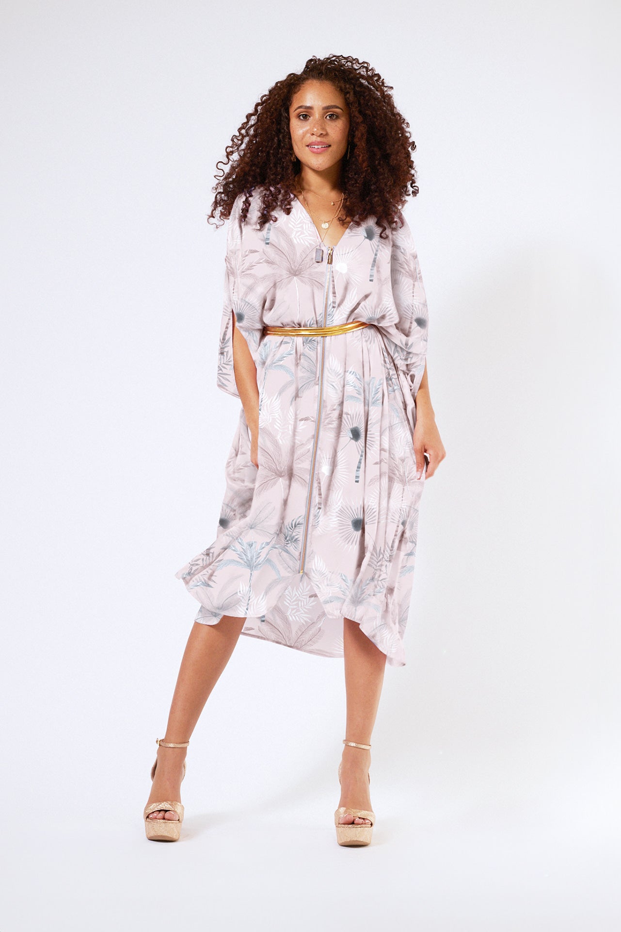 front view of woman wearing all over blush tropical print kaftan duster with front zipper made from recycled materials 3