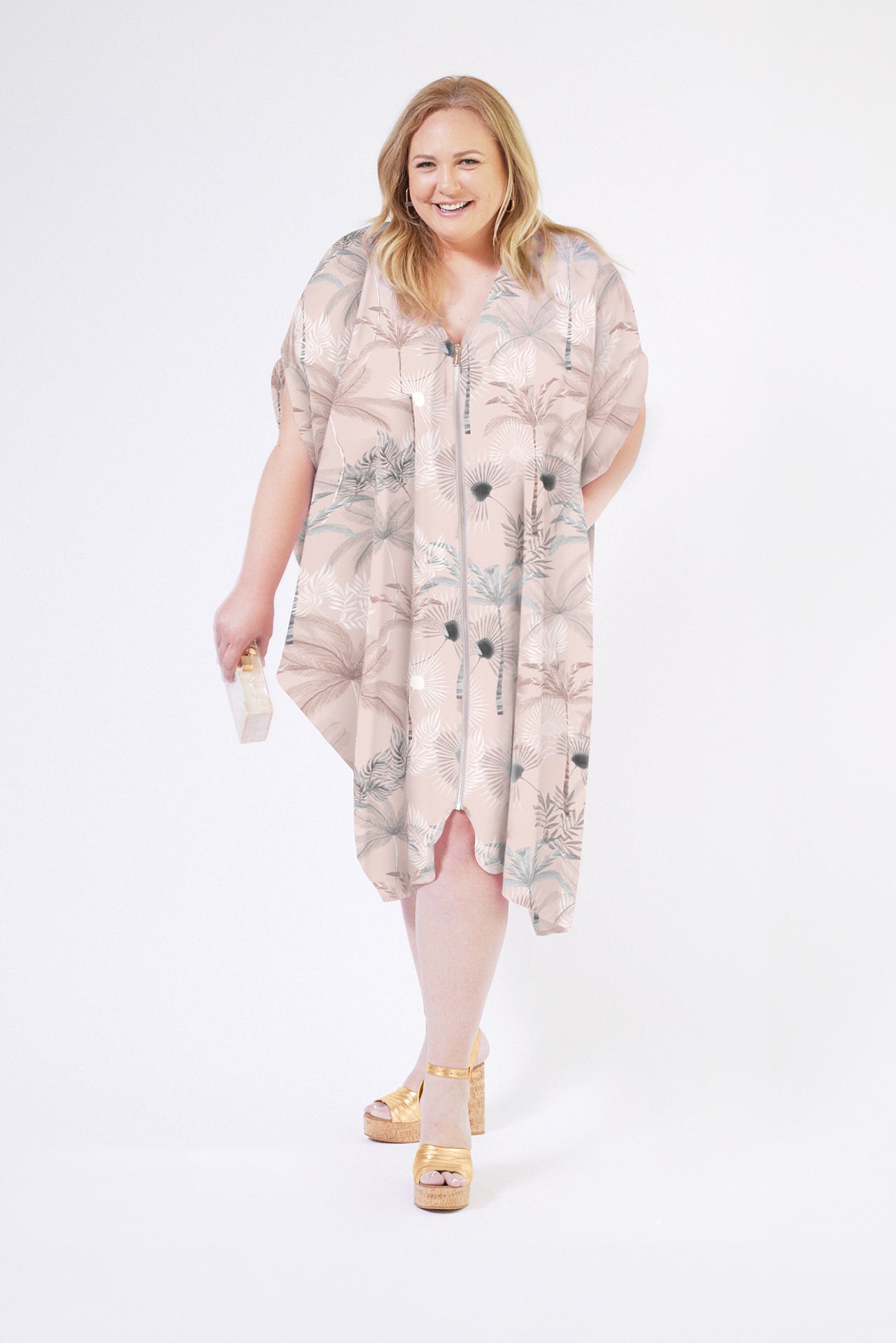 front view of woman wearing all over blush tropical print kaftan duster with front zipper made from recycled materials 5