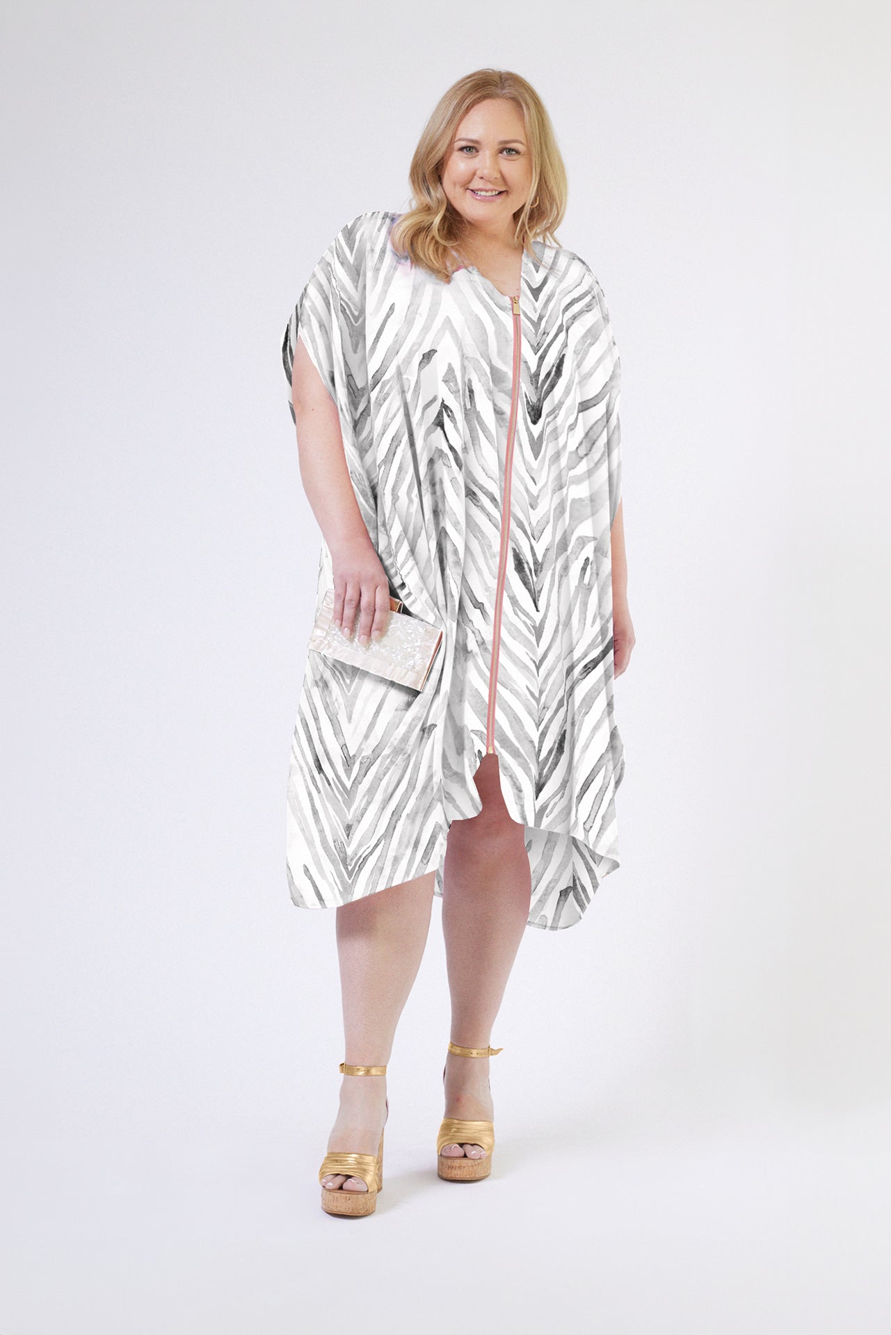 front view of woman wearing an all over grey and white zebra print kaftan duster with zipper made from recycled materials