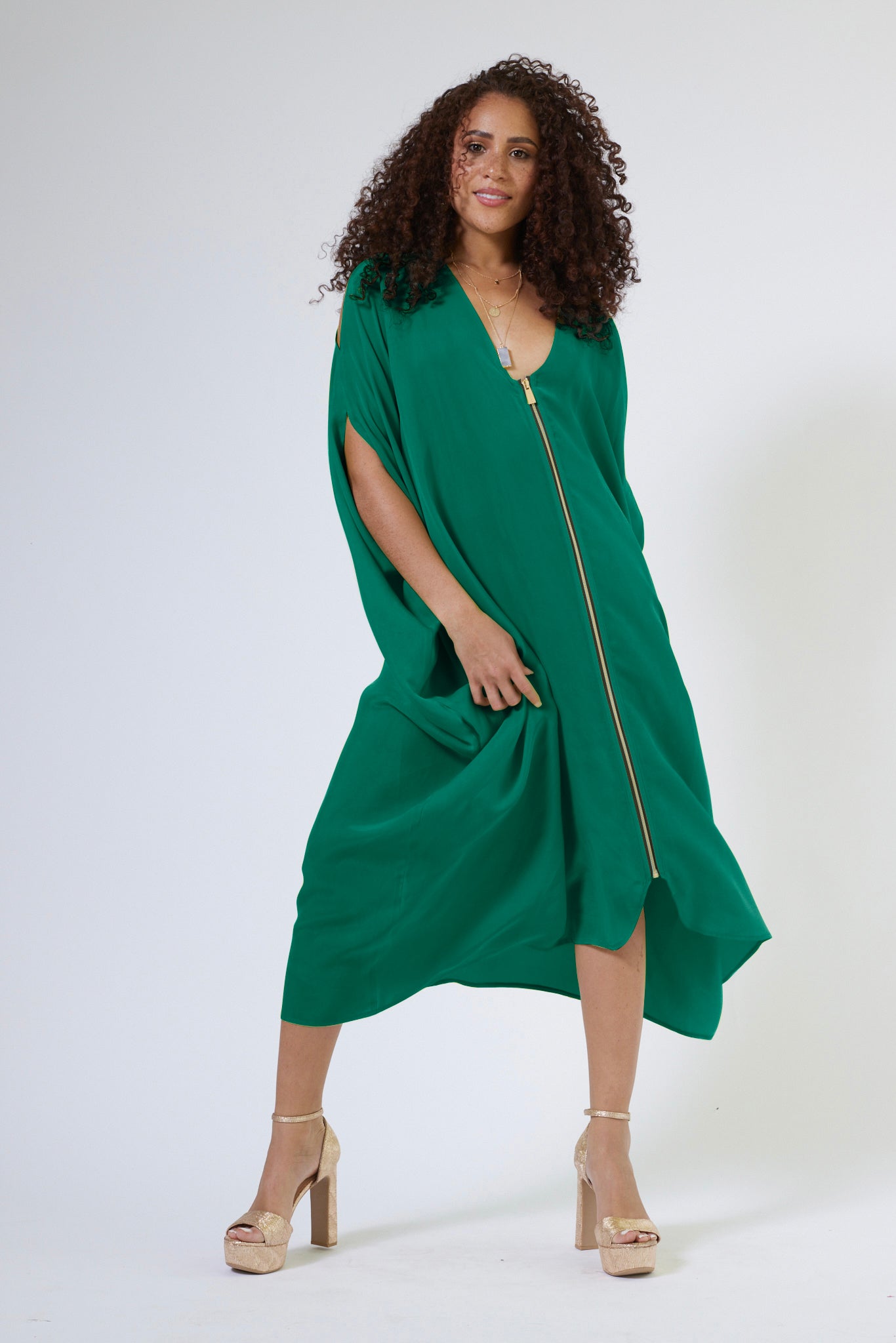 front profile view of woman wearing green kaftan duster with front zipper made from recycled materials