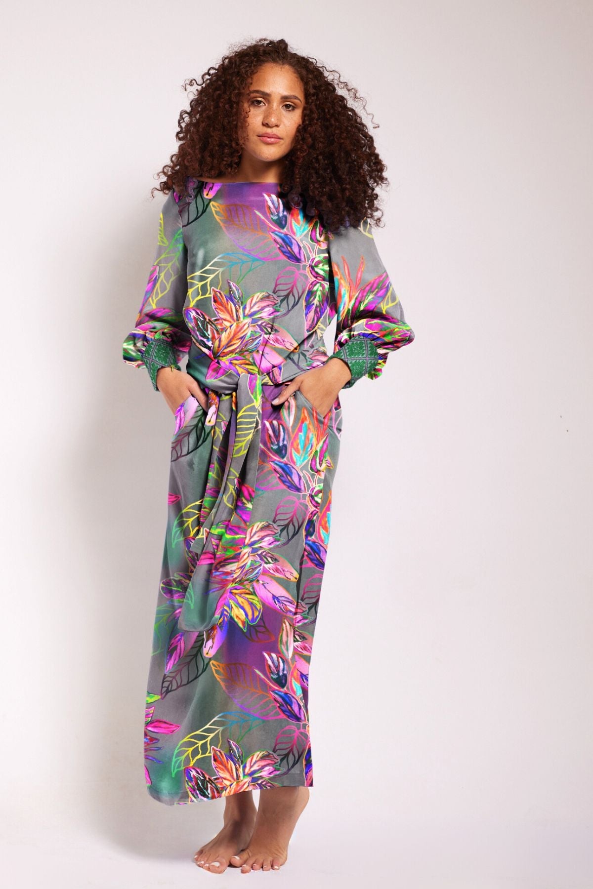 front profile of woman wearing all over tropical printed kaftan duster with embroidered cuffs made from recycled materials