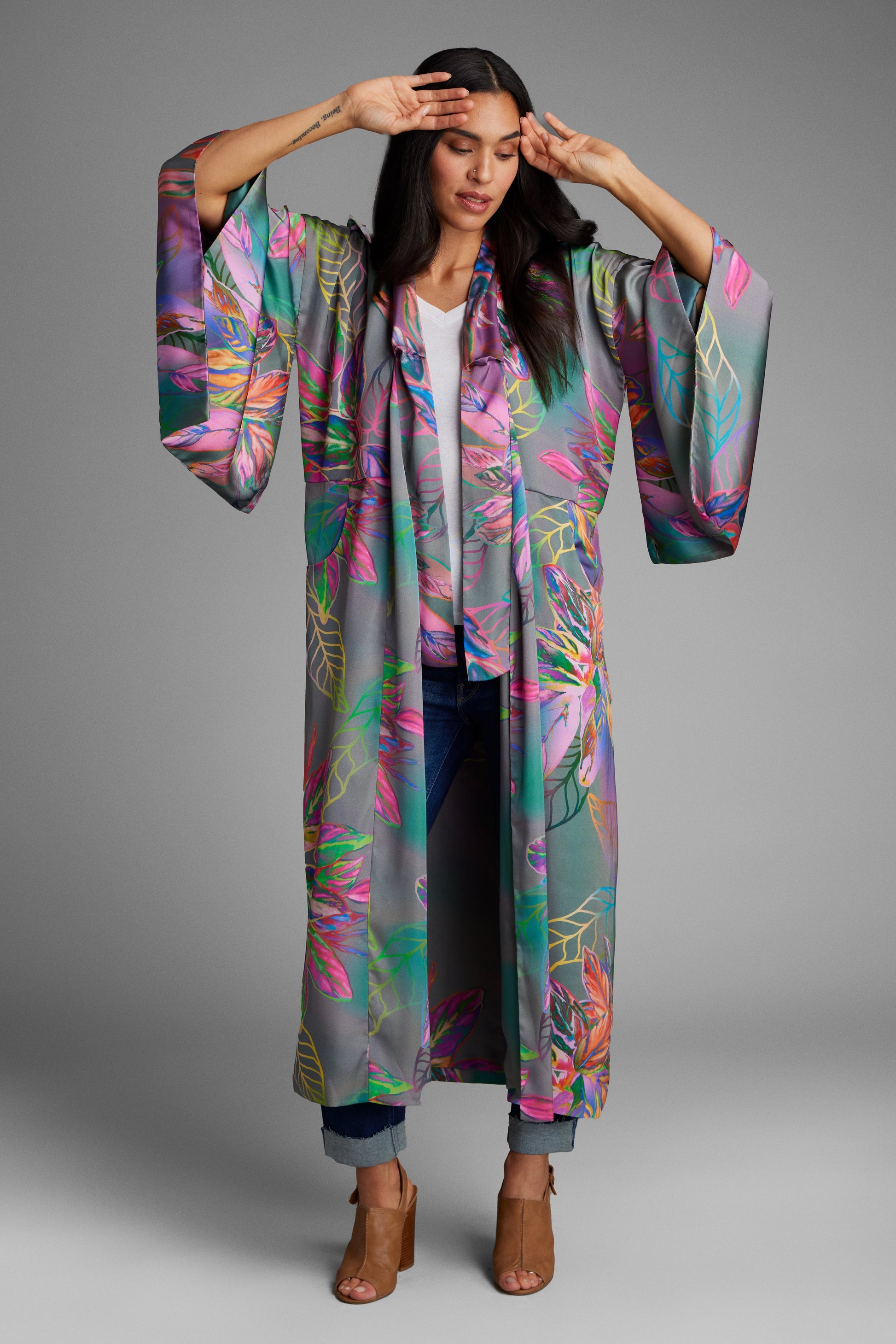 Woman standing with hands on her face wearing an all over tropical printed kimono duster made from recycled materials