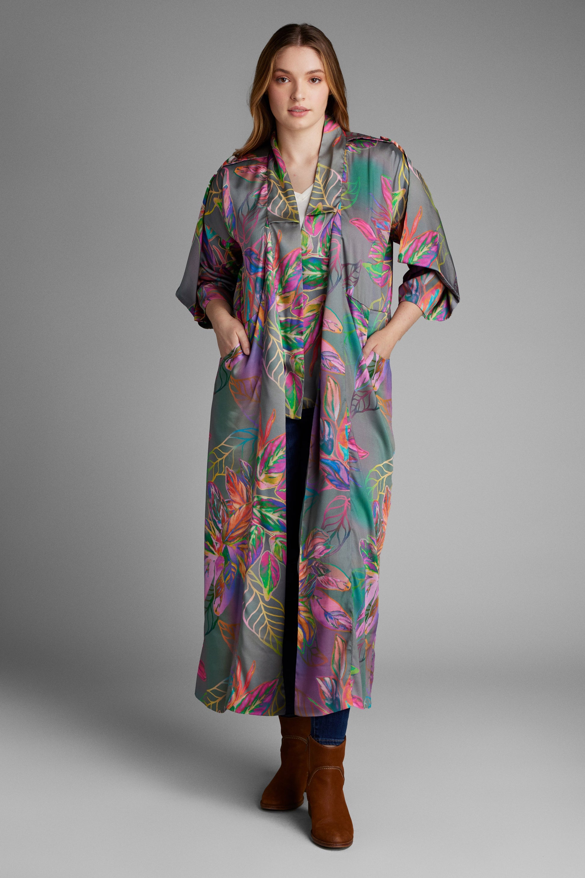 Woman standing with hand in pocket wearing an all over tropical print kimono duster made from recycled materials 3
