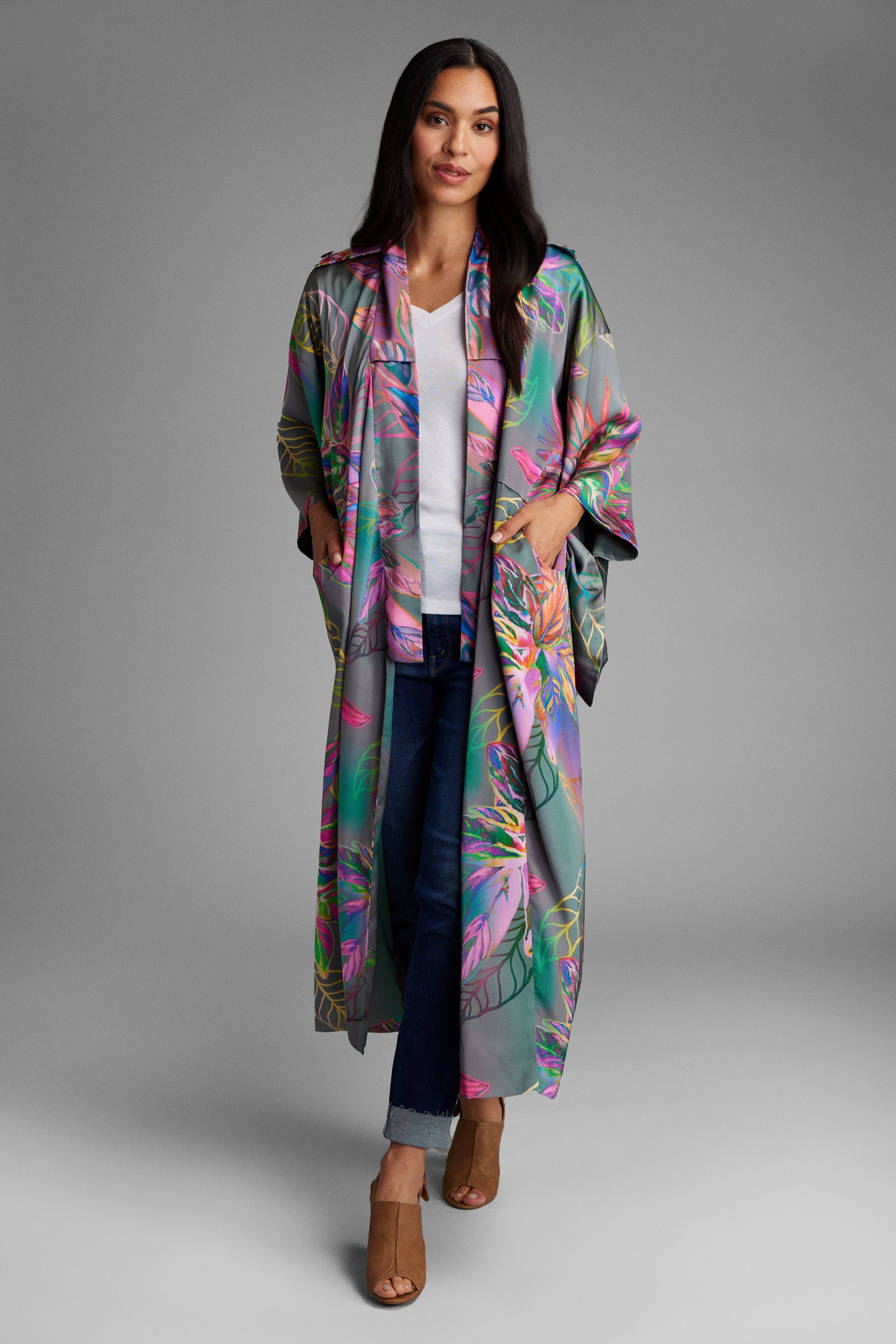 Woman standing with hand in pocket wearing an all over tropical print kimono duster made from recycled materials