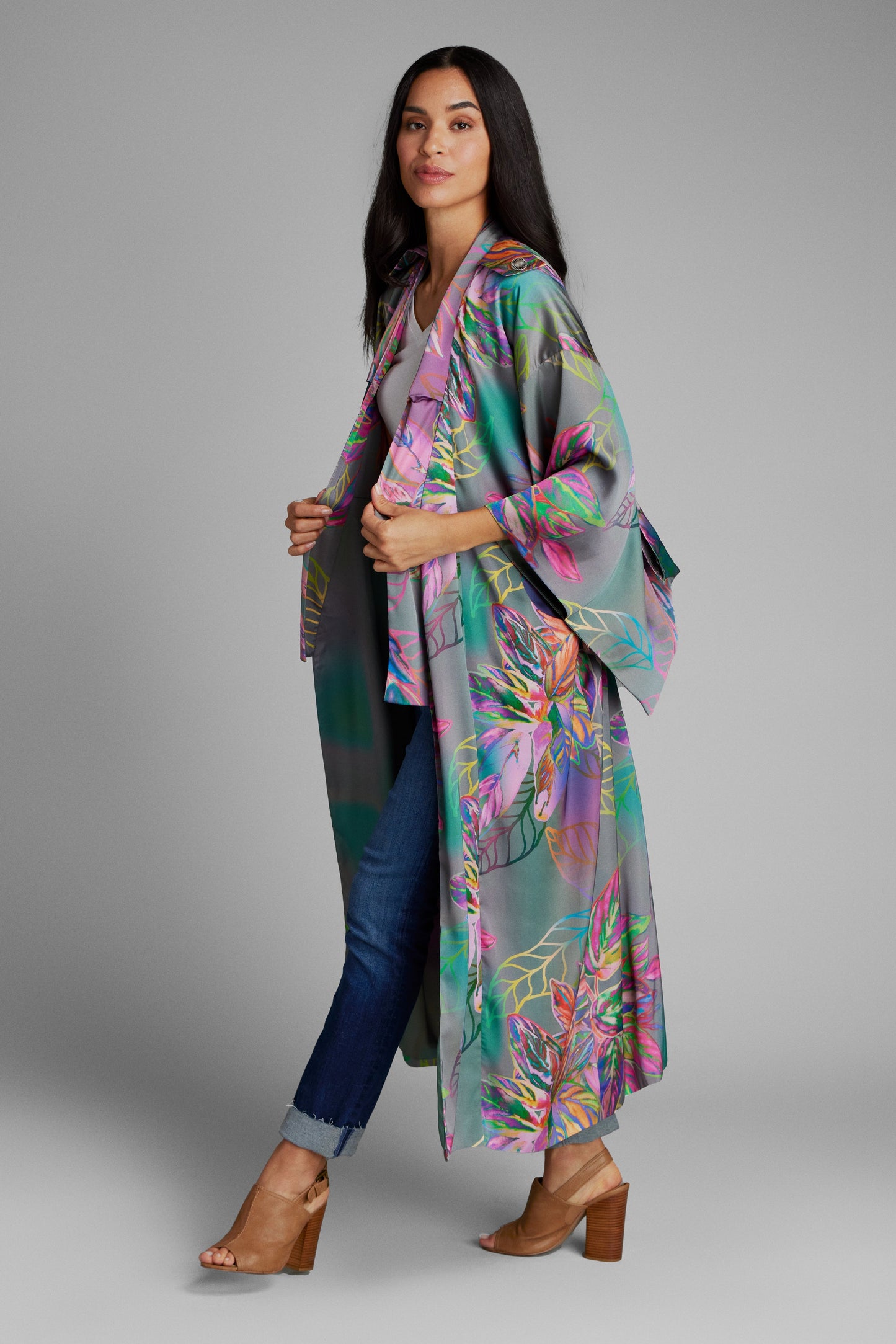 Woman standing wearing an all over tropical printed kimono duster made from recycled materials