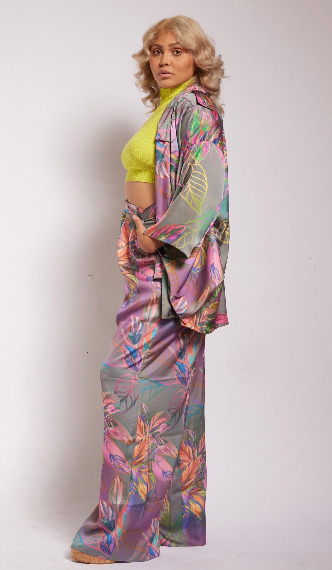 Side profile of woman wearing all over tropical printed kimono duster and matching yacht pants made from recycled materials
