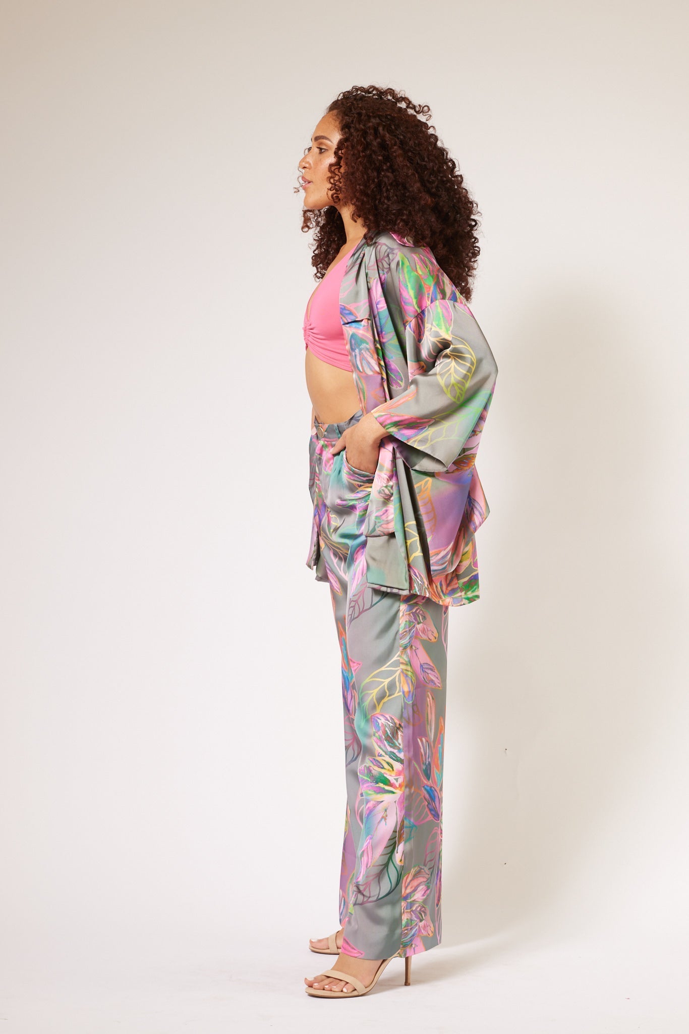 Side profile of woman wearing an all over tropical print kimono duster and yacht pants made from recycled materials
