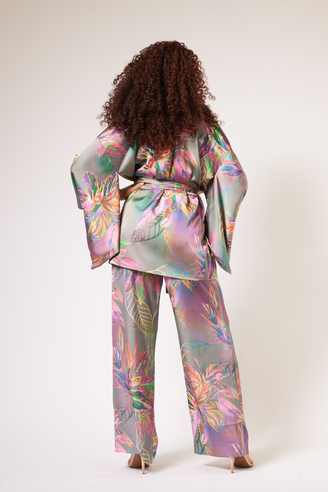 Back view profile of woman wearing an all over tropical print kimono duster and yacht pants made from recycled materials 2