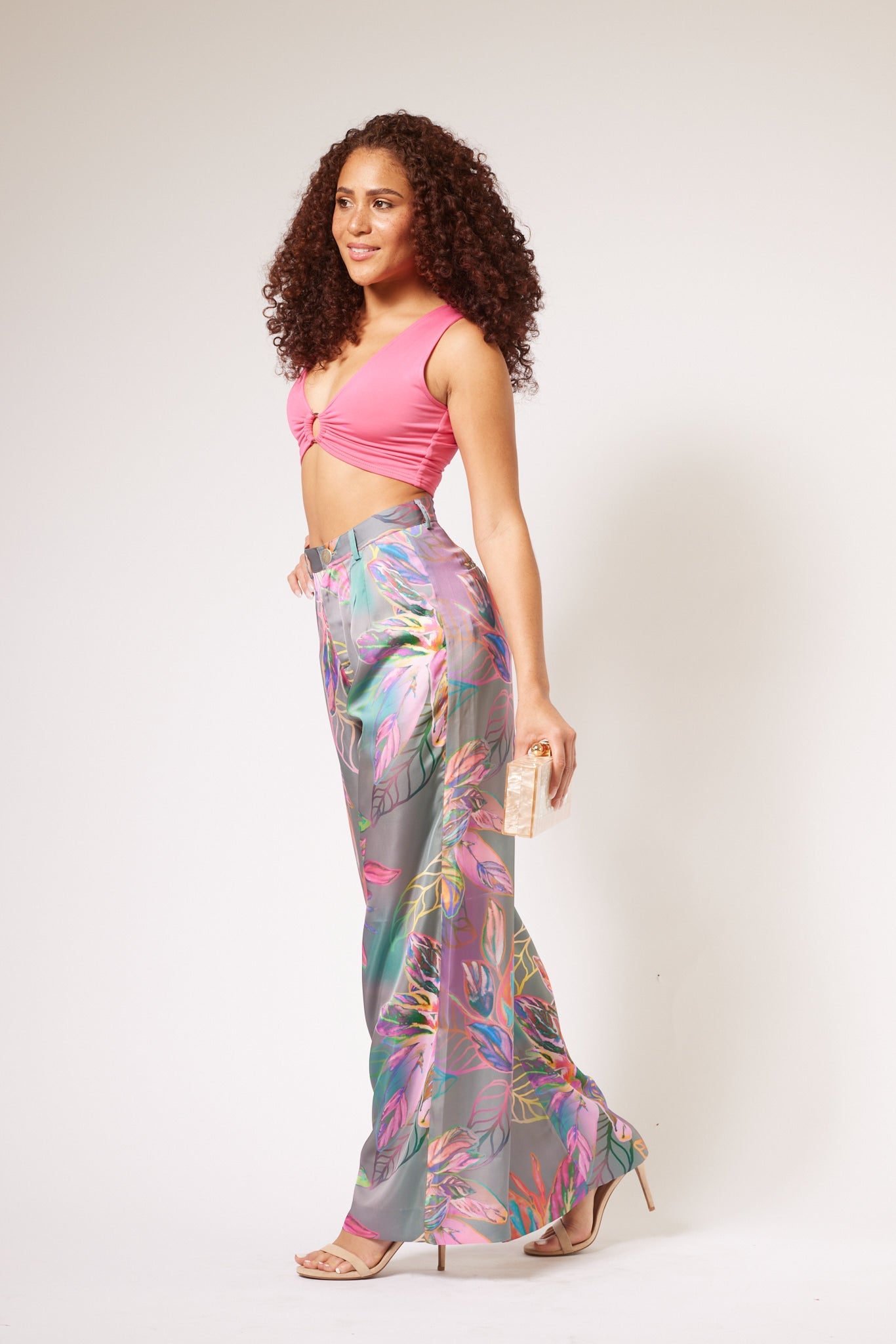 side view of woman modelling all over multicolored tropical yacht pants with clutch purse