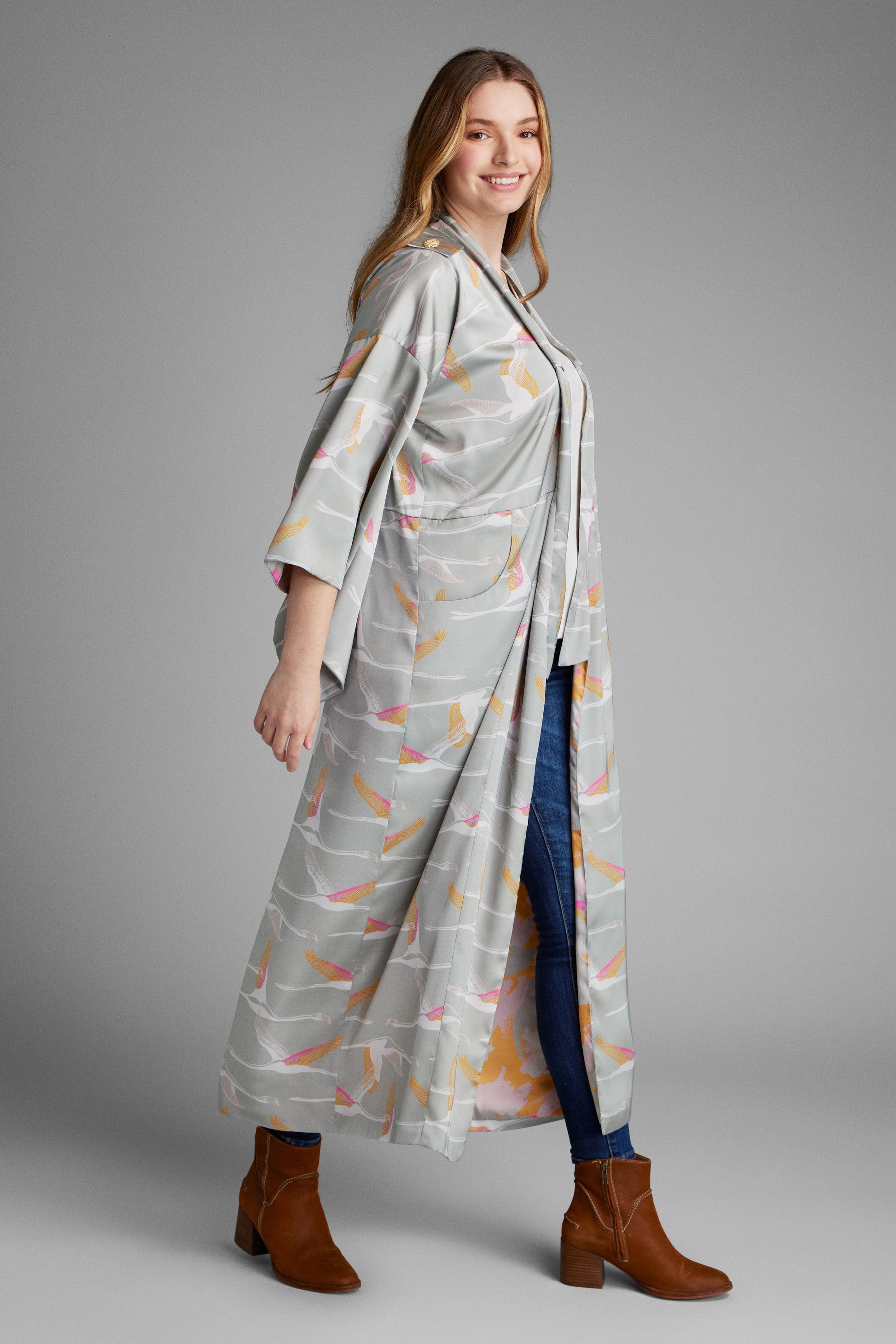 Side profile view of woman wearing a grey pink and gold colored crane print kimono duster made from recycled materials