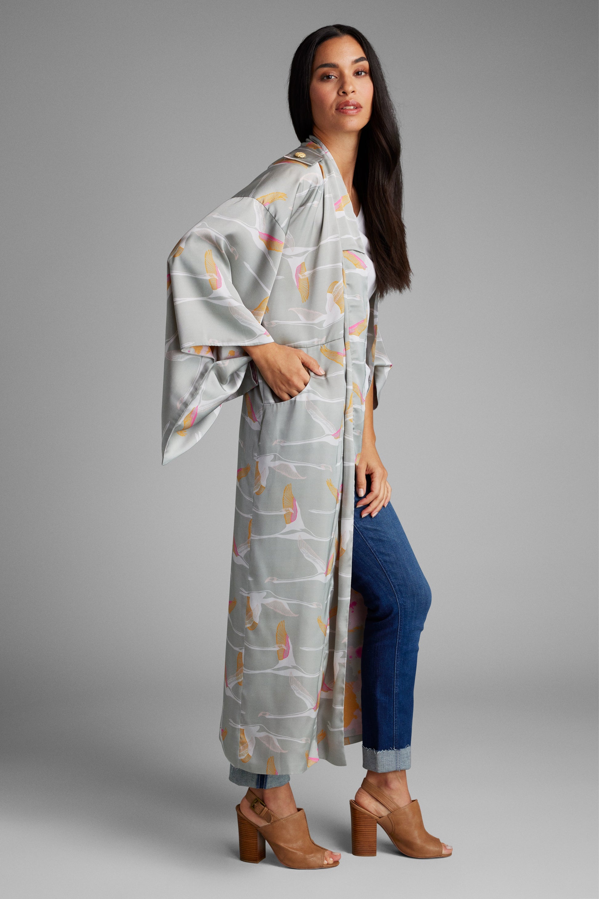 woman standing with hands on her face wearing a grey and pink colored crane patterned kimono duster made from recycled materials 2