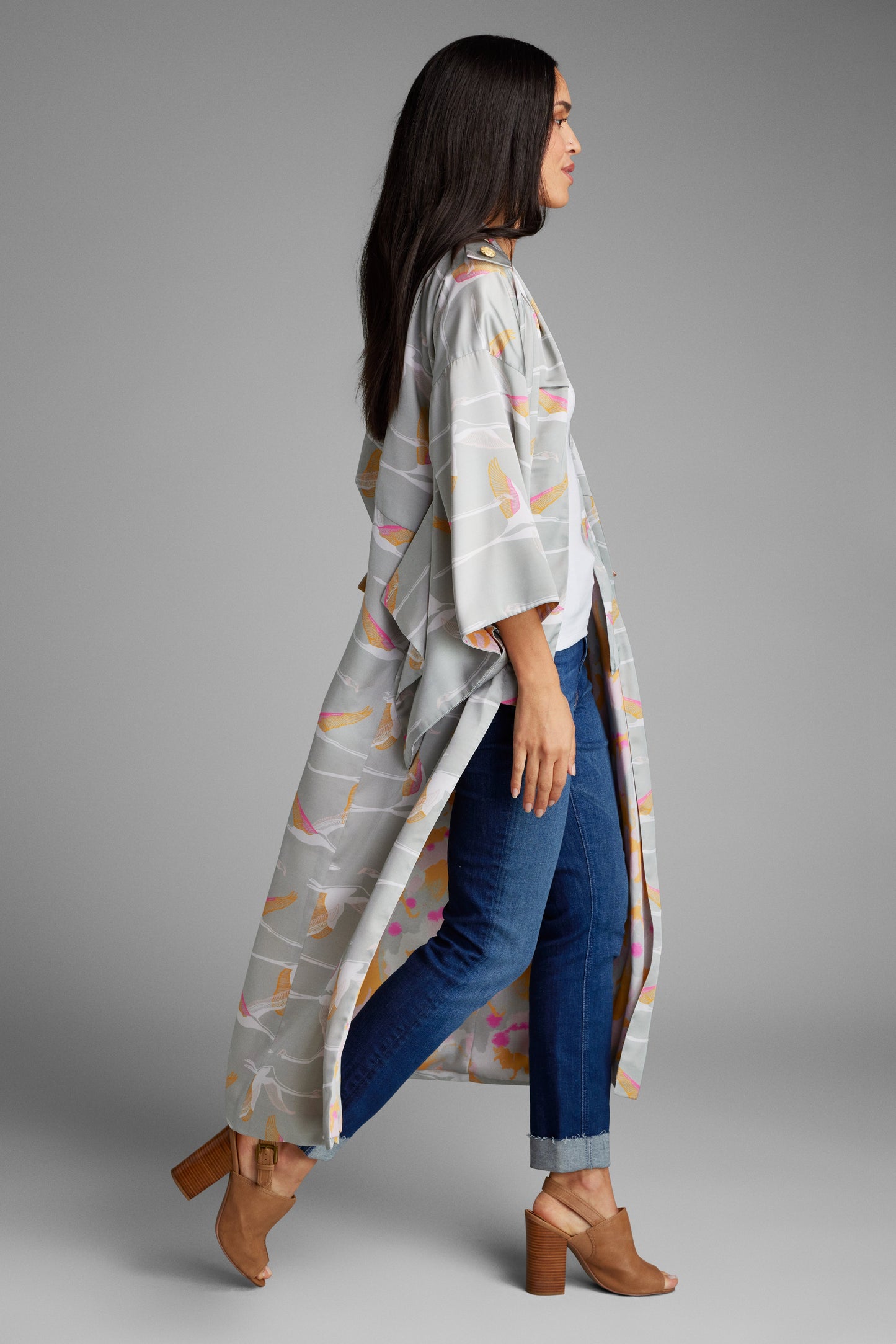 woman standing with hands on her face wearing a grey and pink colored crane patterned kimono duster made from recycled materials 3