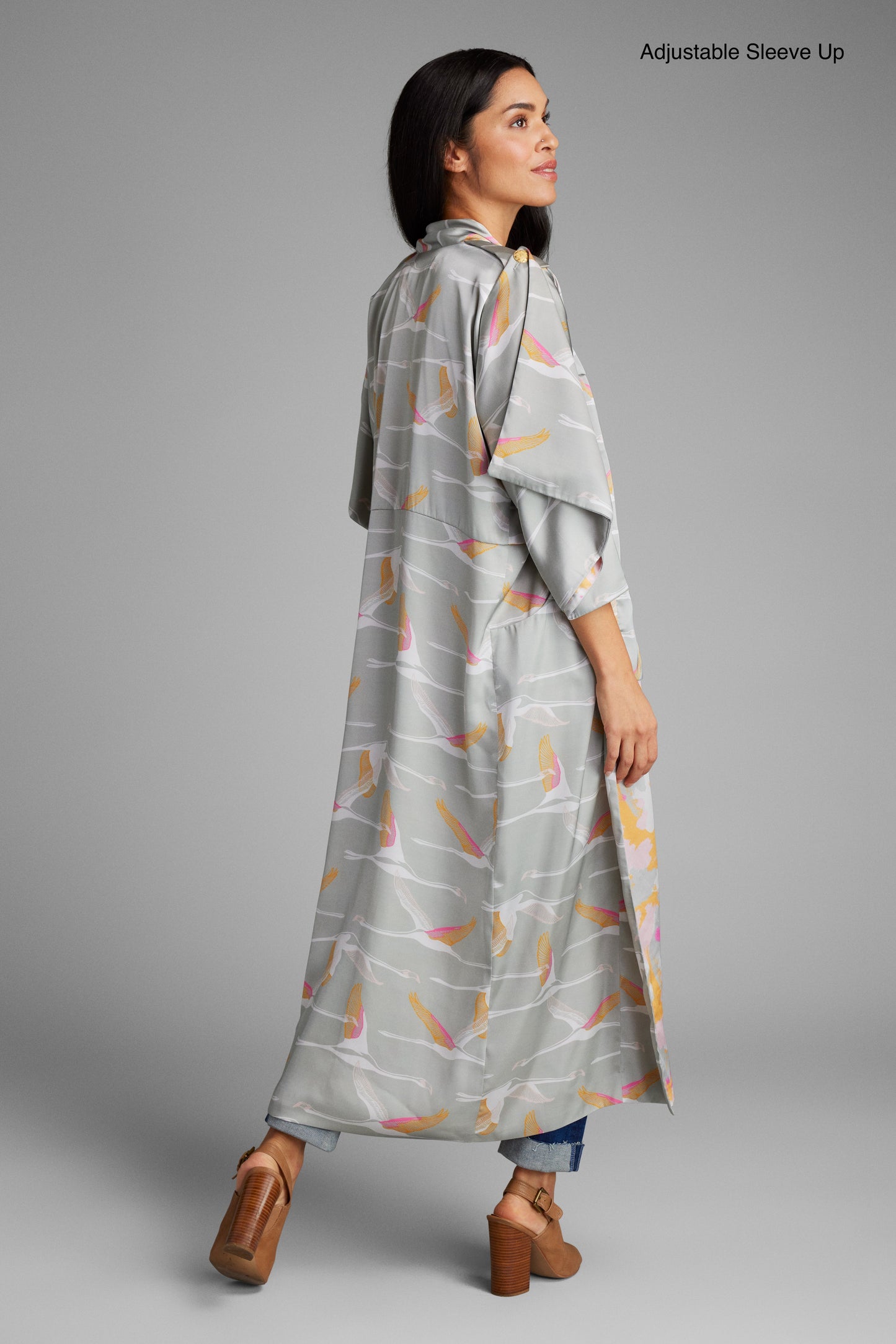 Back profile view of woman wearing a grey pink and gold colored crane print kimono duster made from recycled materials