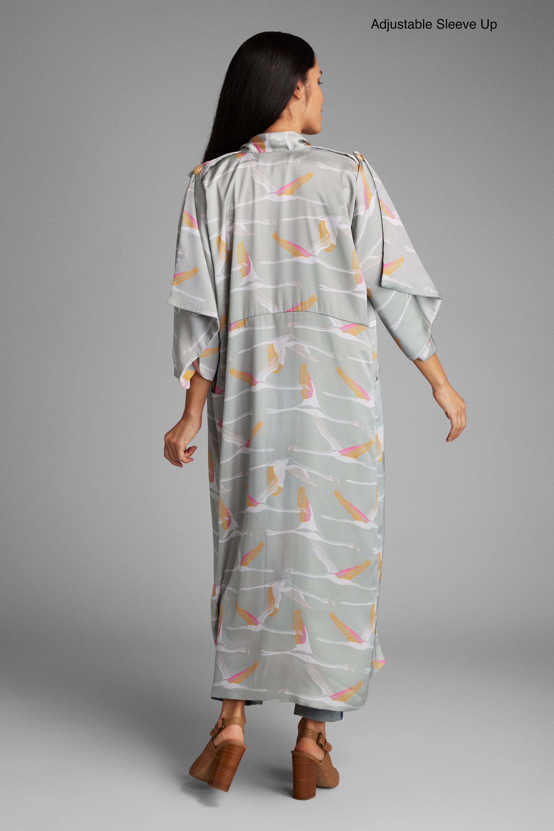 Back profile view of woman wearing a grey pink and gold colored crane print kimono duster made from recycled materials 2