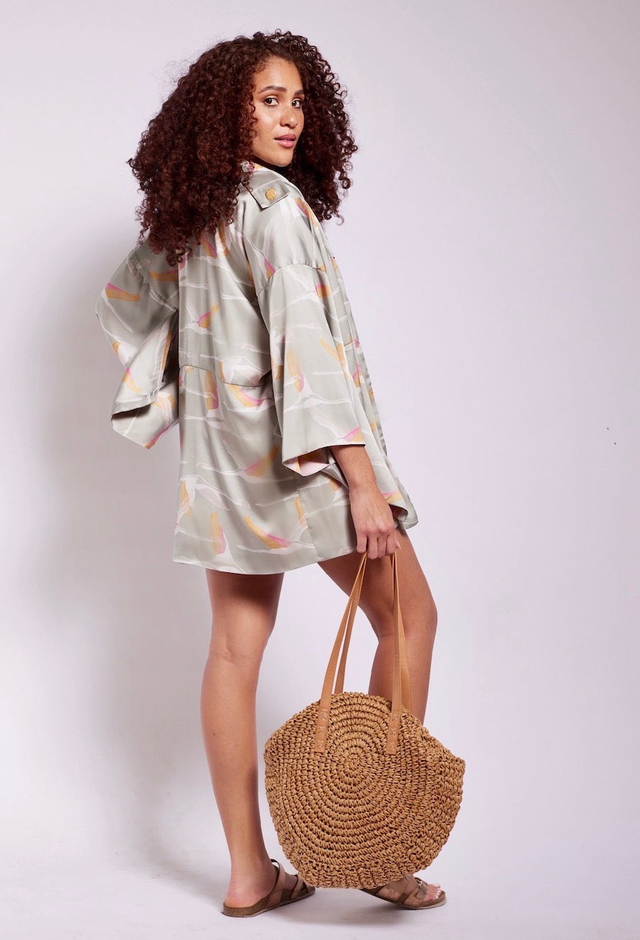 back view of woman wearing a grey pink and gold colored crane printed kimono duster made from recycled materials