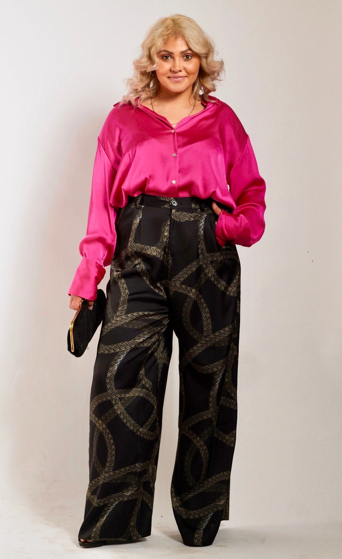 front profile of woman wearing black and gold chain printed yacht slacks and pink blouse