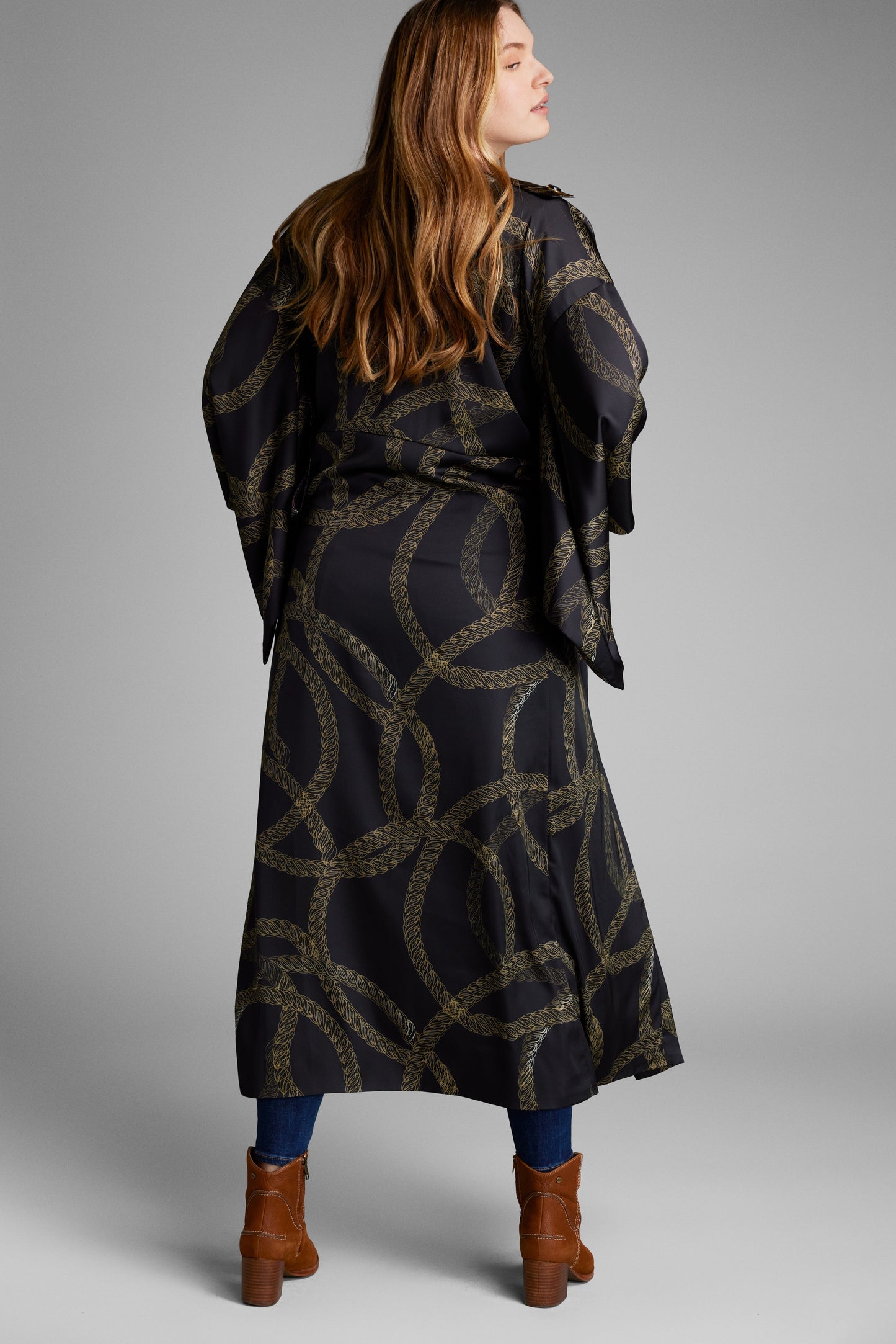 Side profile of woman wearing a black and gold chain print kimono duster made from recycled materials