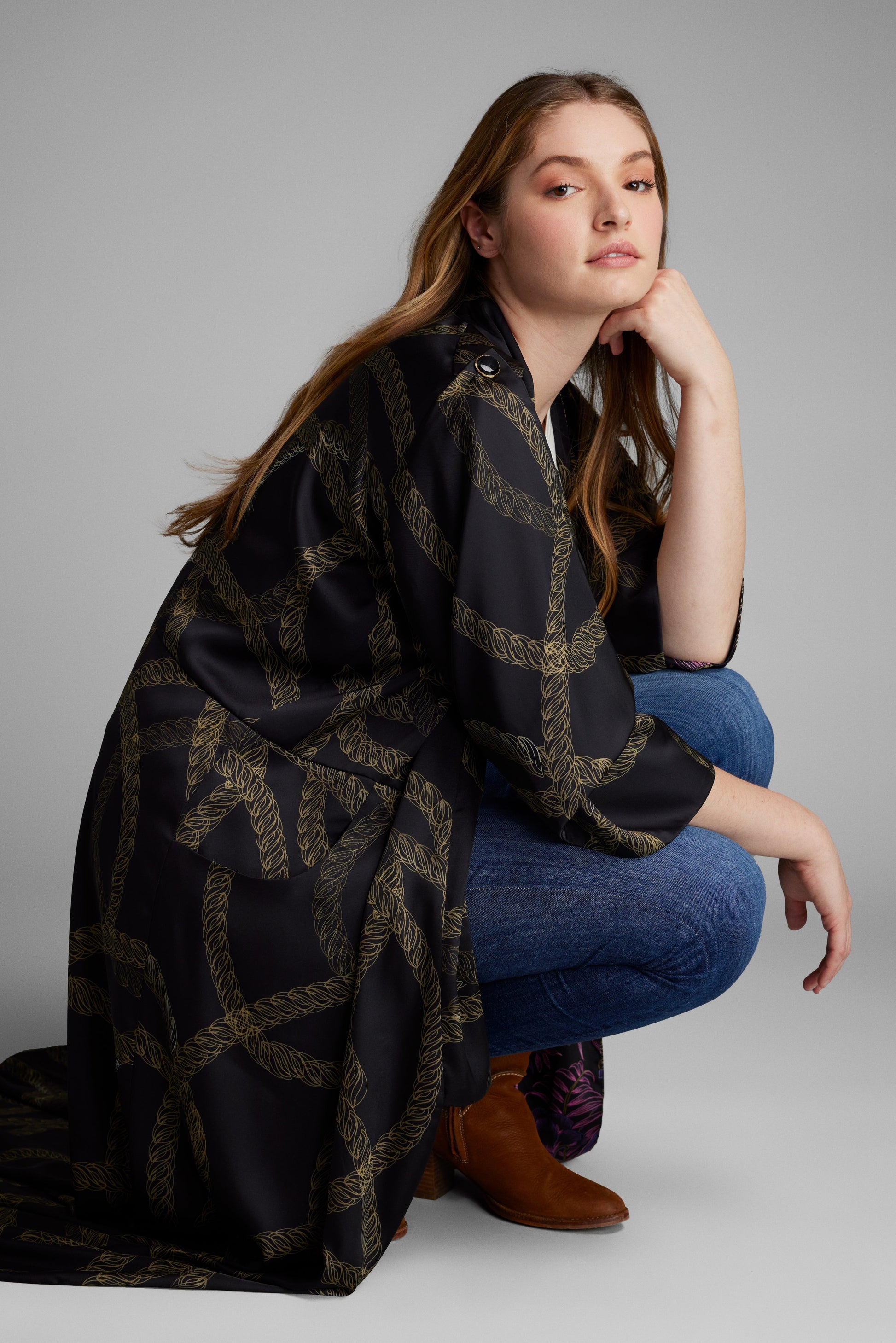 Woman kneeling down with a black and gold chain printed kimono duster made from recycled materials 2