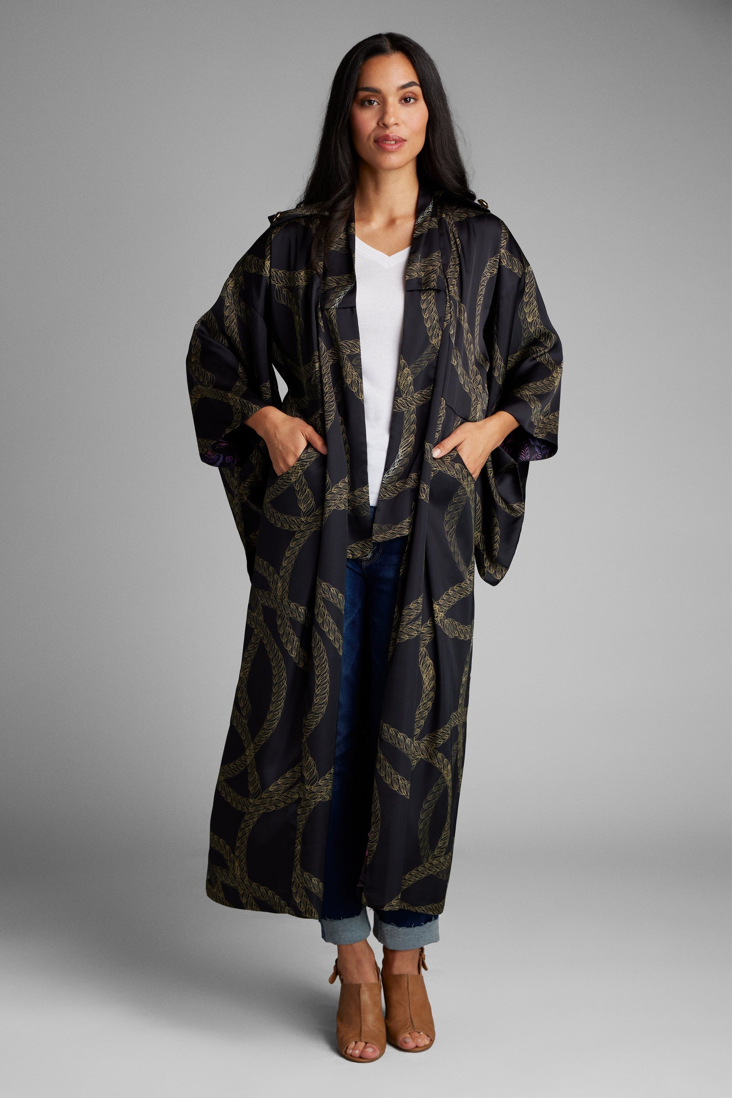 Woman with her hands in her pockets wearing a black and gold chain printed kimono duster made from recycled materials
