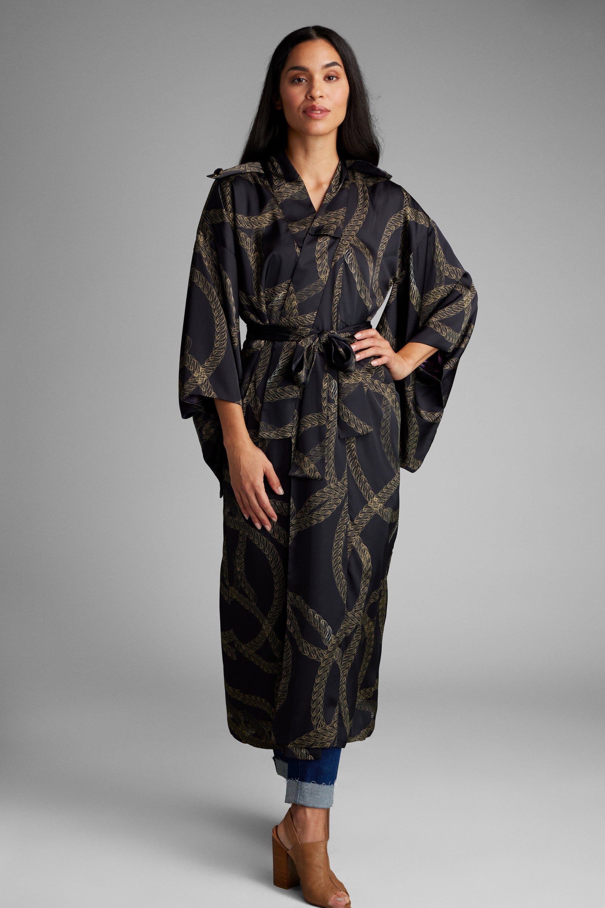 Woman with her hands in her pockets wearing a black and gold chain printed kimono duster made from recycled materials 2