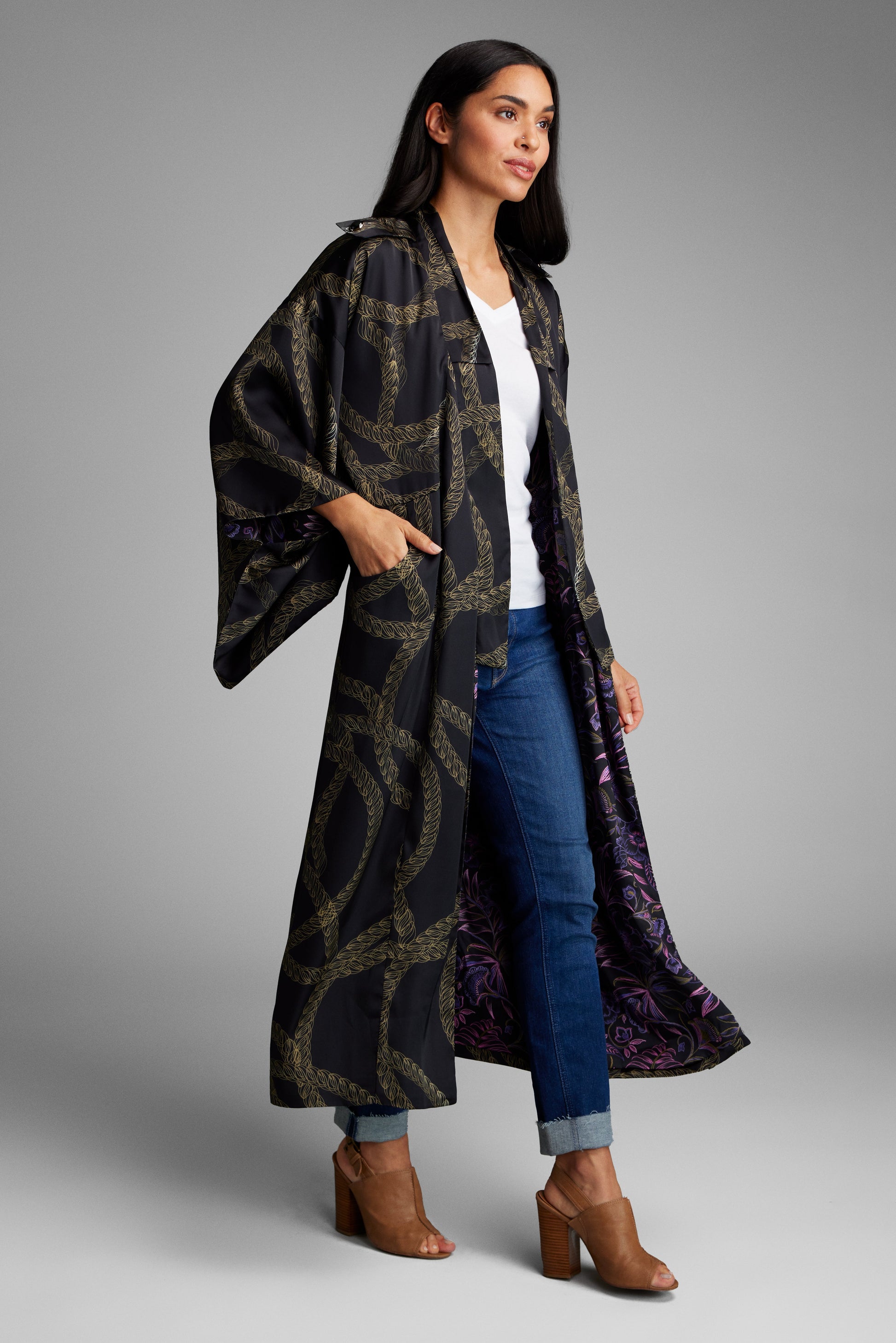 Woman with her hands in her pockets wearing a black and gold chain printed kimono duster made from recycled materials 3