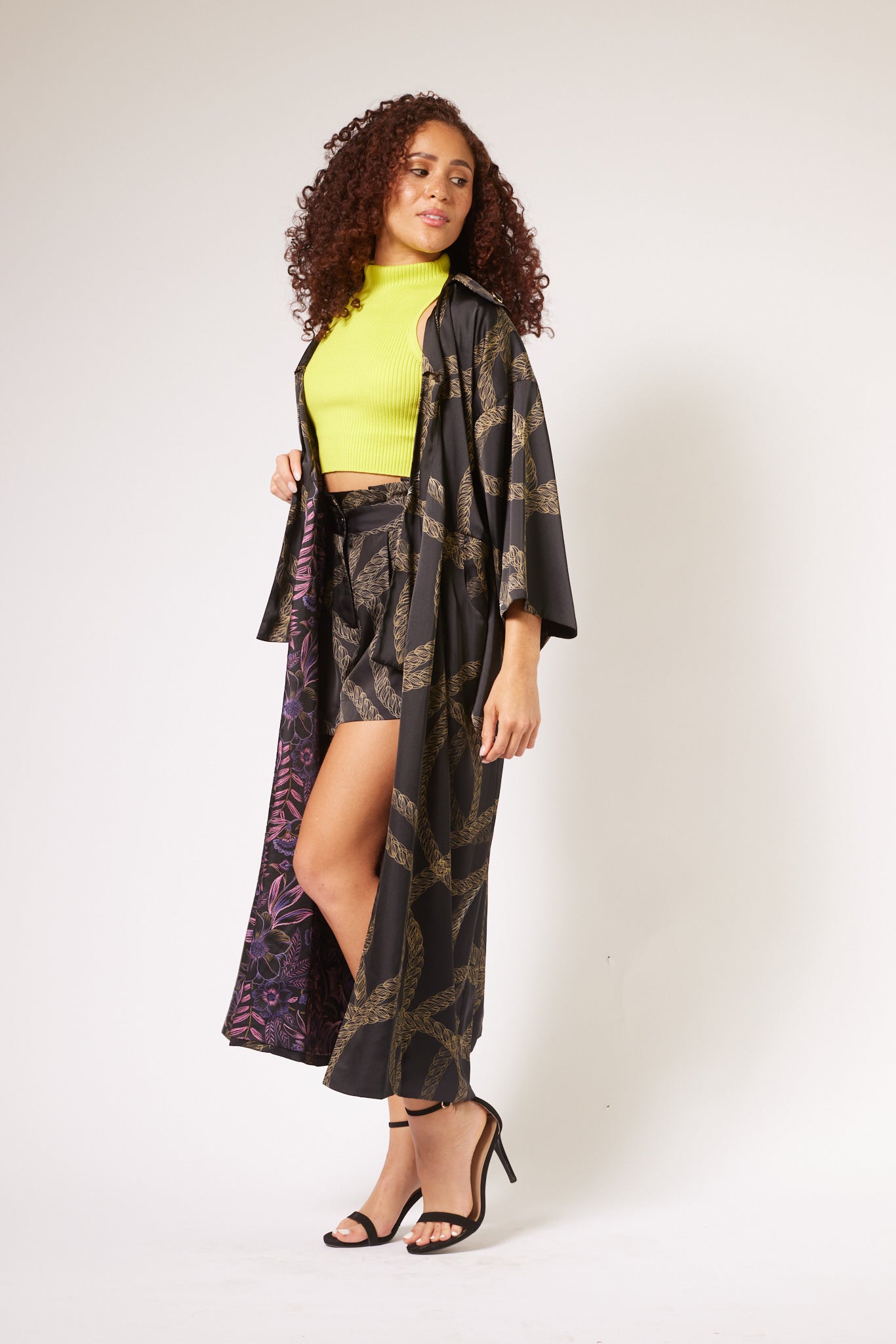 woman wearing gold and black chain printed tulip shorts and marching kimono duster made from recycled textiles 2