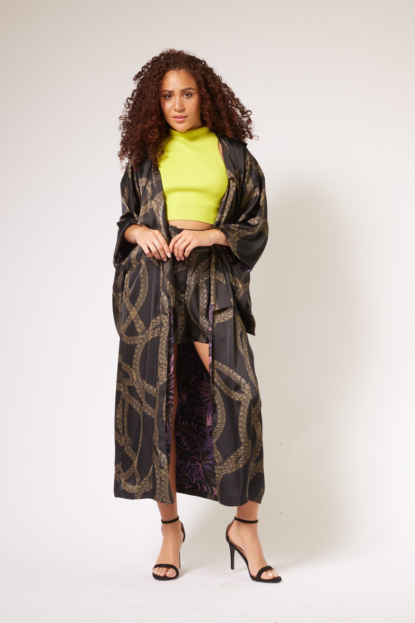 woman wearing gold and black chain printed tulip shorts and marching kimono duster made from recycled textiles 3