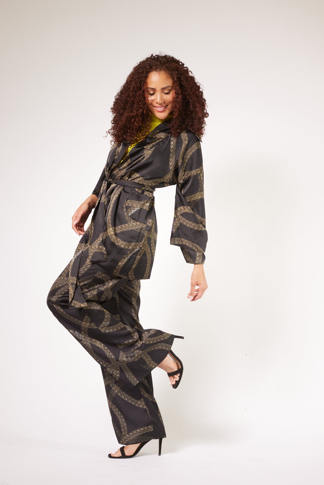 side profile of woman wearing black and gold chain printed yacht slacks and matching kimono duster made from recycled textiles 5