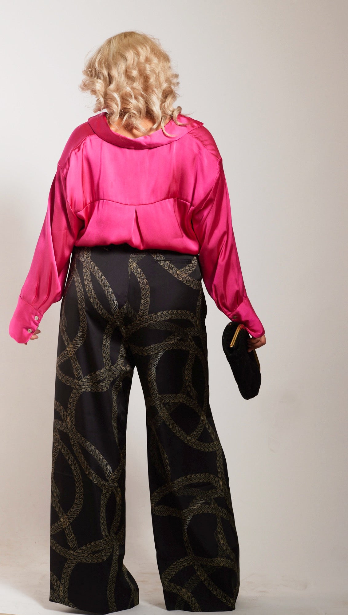 back profile of woman wearing black and gold chain printed yacht slacks and pink blouse