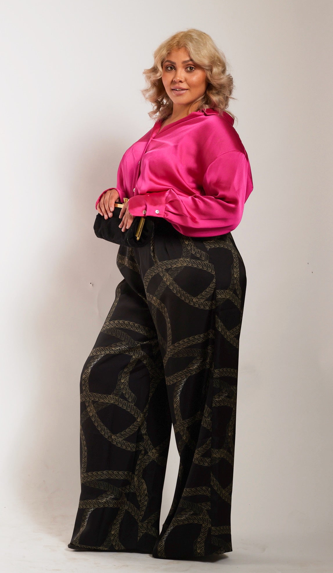 side profile of woman wearing black and gold chain printed yacht slacks and pink blouse