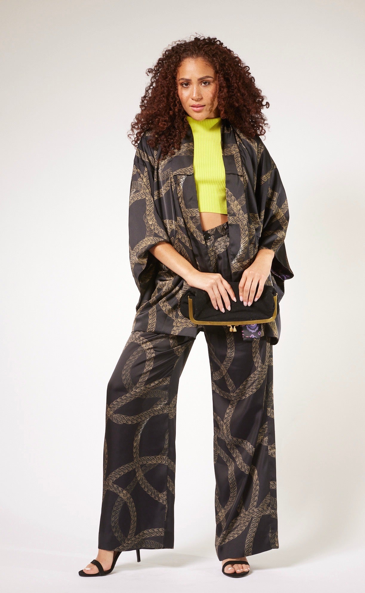 front profile of woman wearing black and gold chain printed yacht slacks and matching kimono duster made from recycled textiles