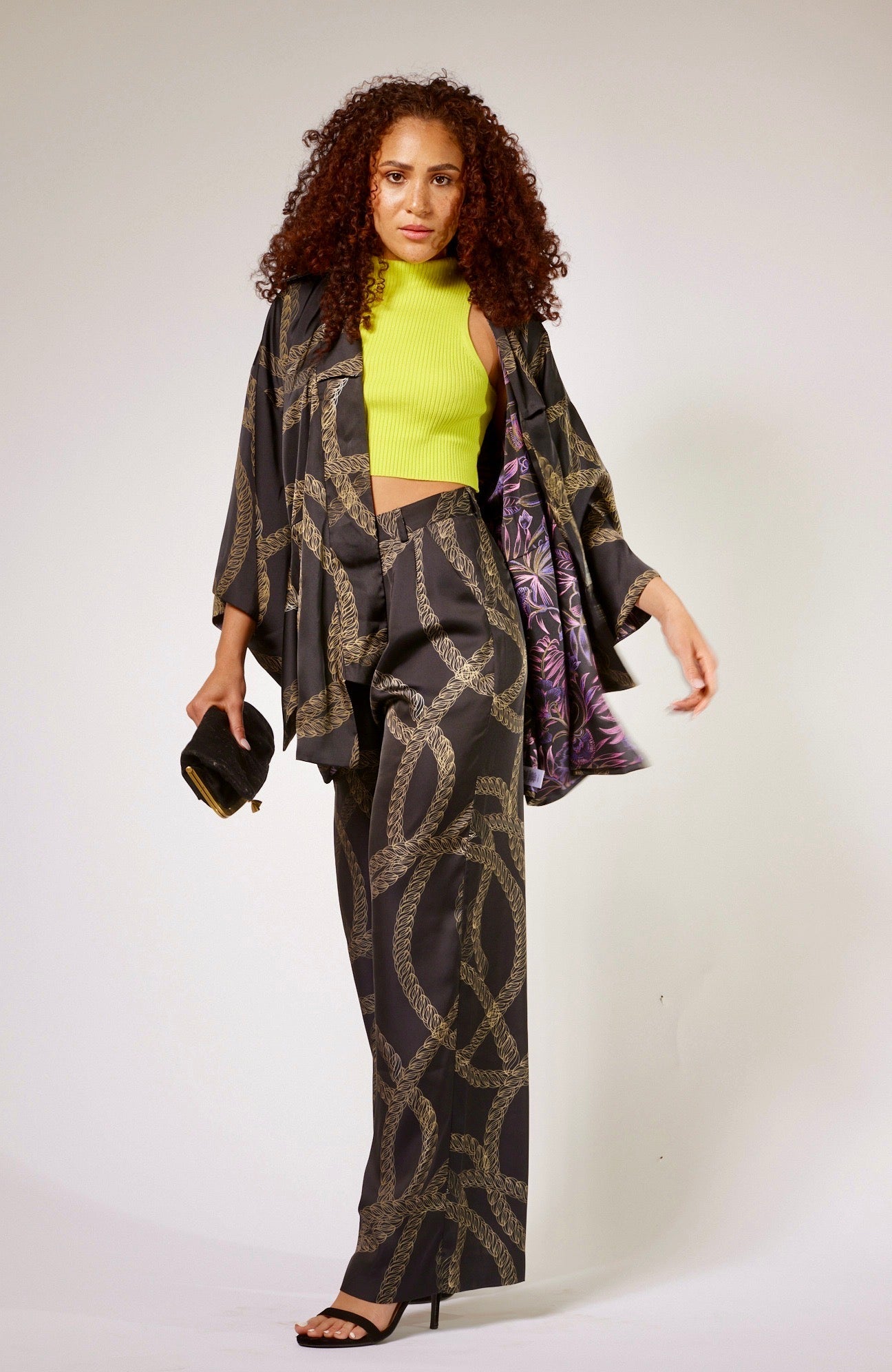 front profile of woman wearing black and gold chain printed yacht slacks and matching kimono duster made from recycled textiles 2