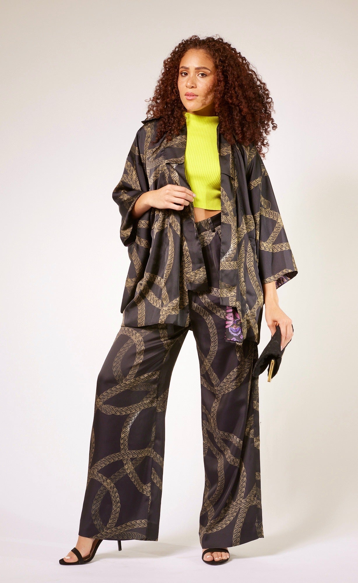 front profile of woman wearing black and gold chain printed yacht slacks and matching kimono duster made from recycled textiles 3