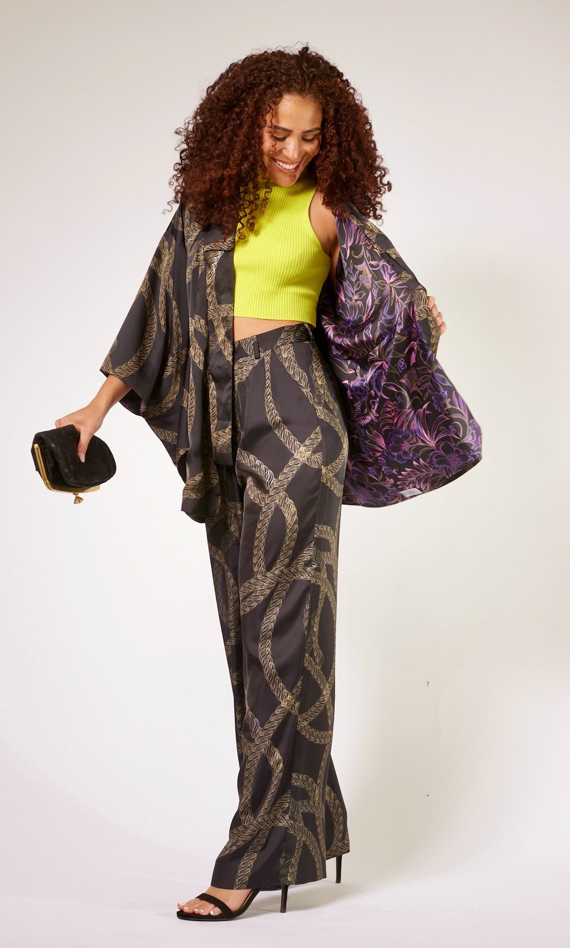 front profile of woman wearing black and gold chain printed yacht slacks and matching kimono duster made from recycled textiles 4